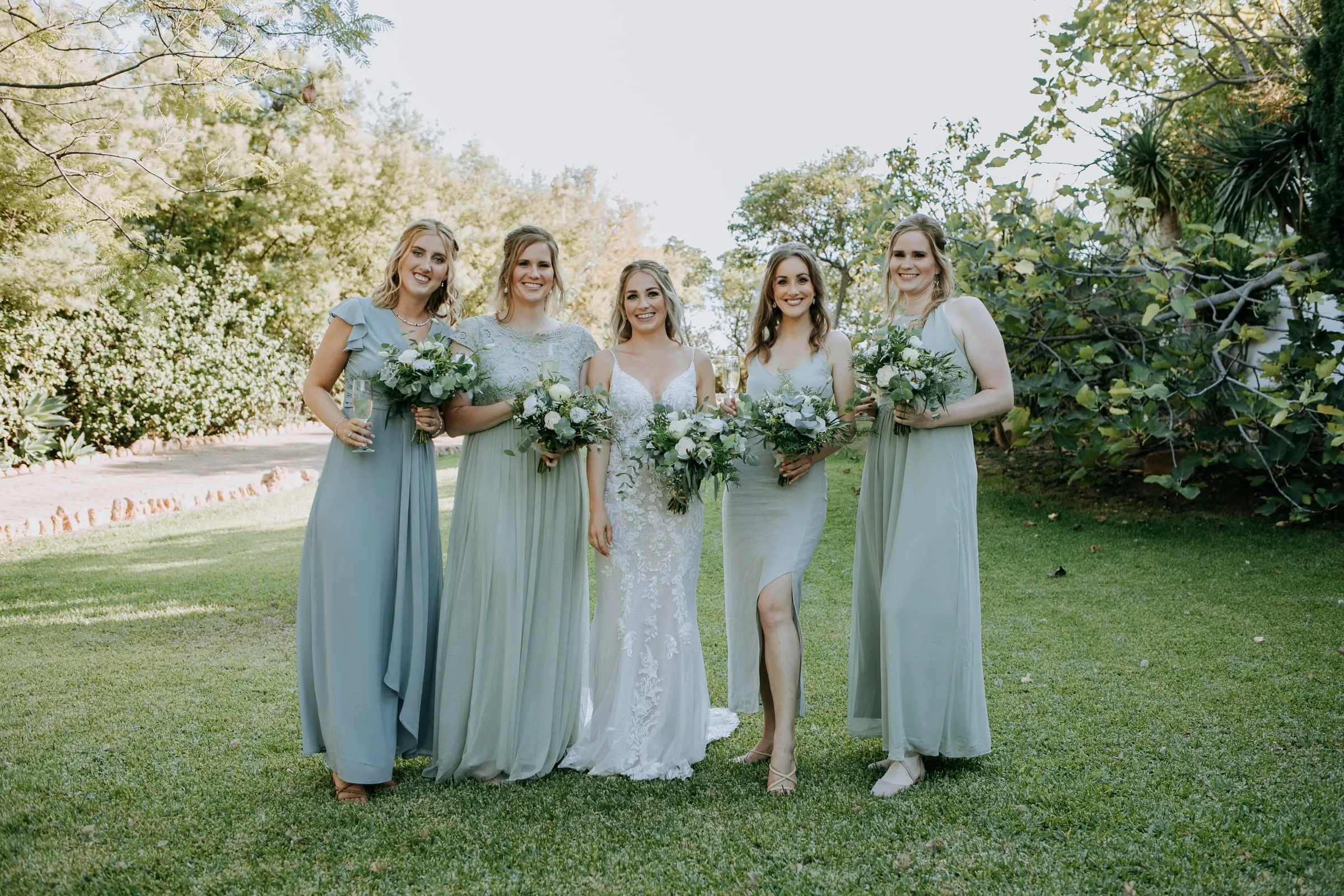 La novia y sus cuatro damas de verde y azul claro caminan por el césped, Hacienda San José, Mijas