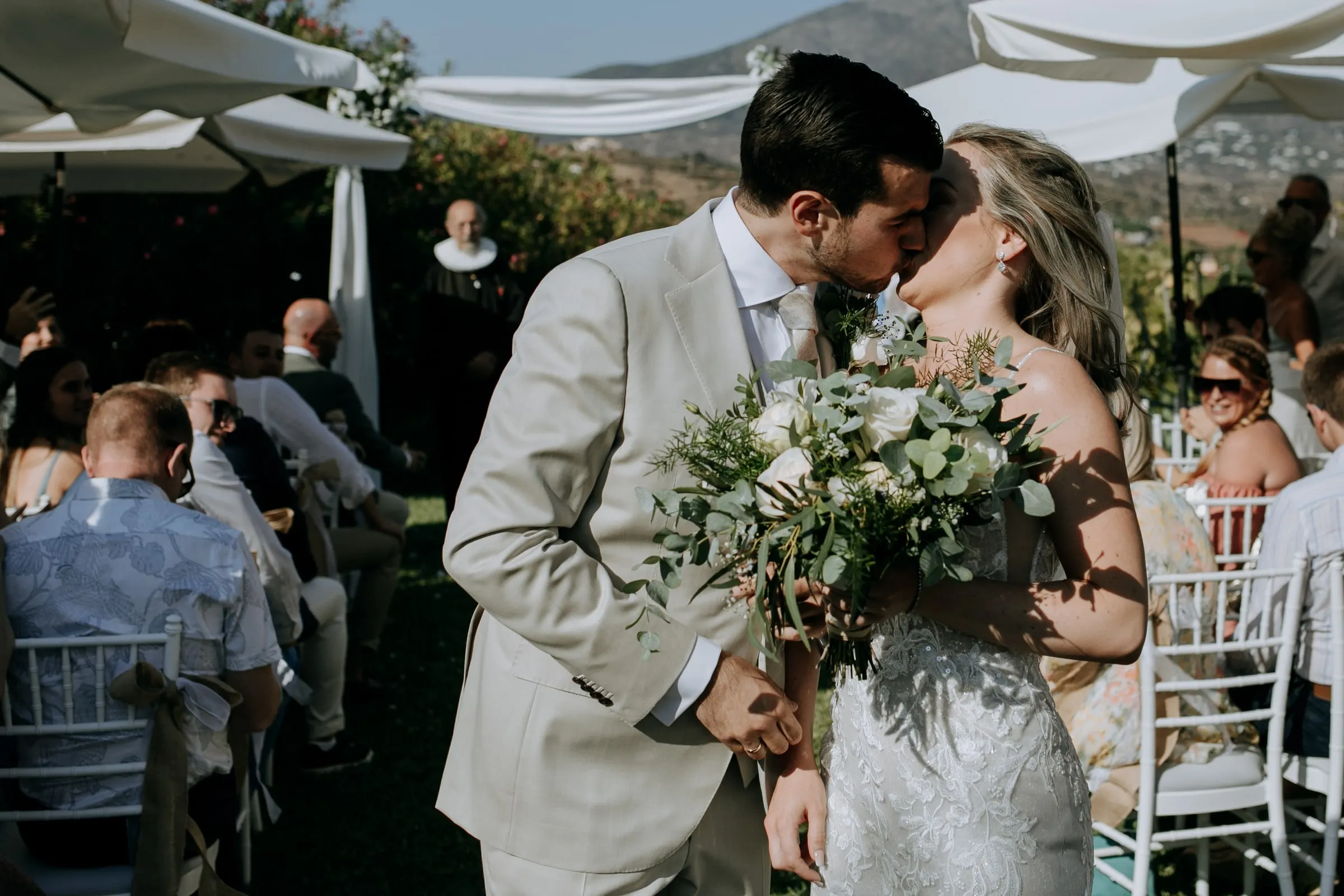 El novio besa a la novia mientras salen por el pasillo entre los invitados, Hacienda San José, Mijas