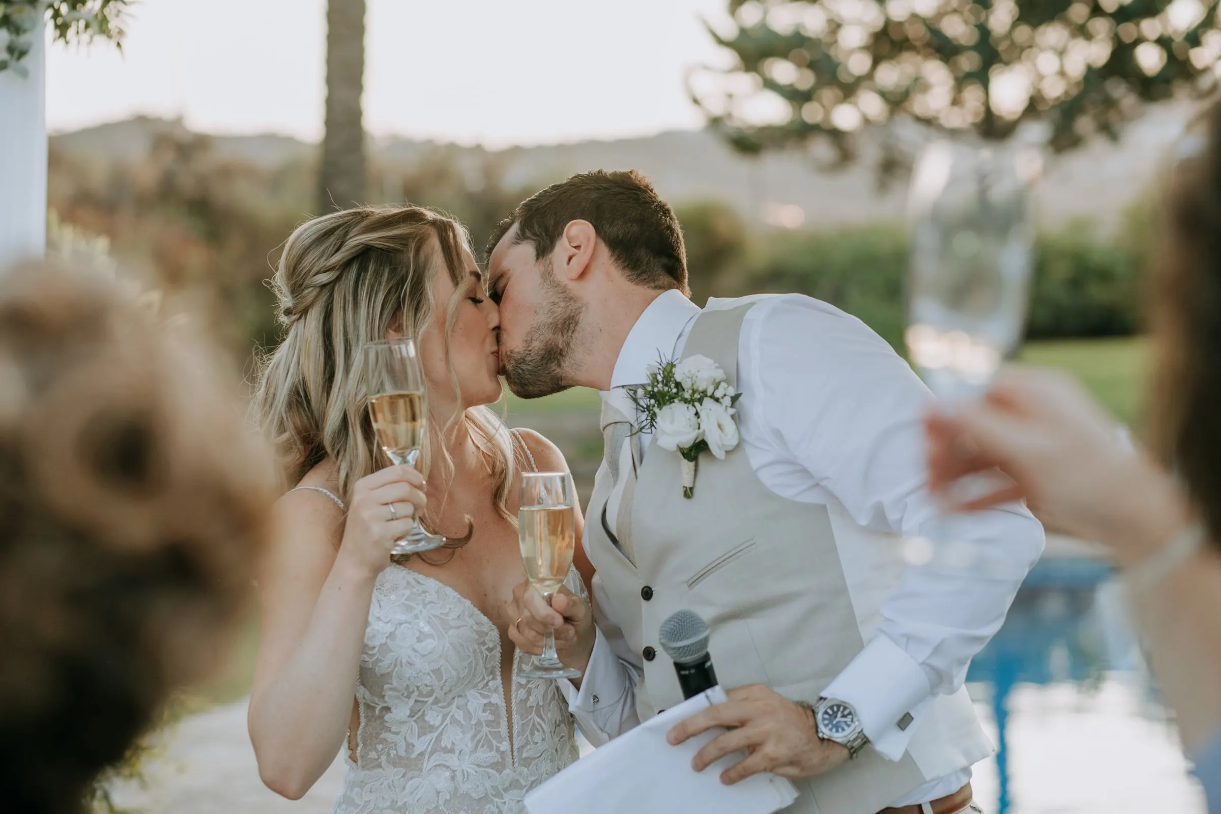 Los novios se besan en pleno brindis, copa de cava en mano, mientras los invitados alzan las suyas, Hacienda San José, Mijas