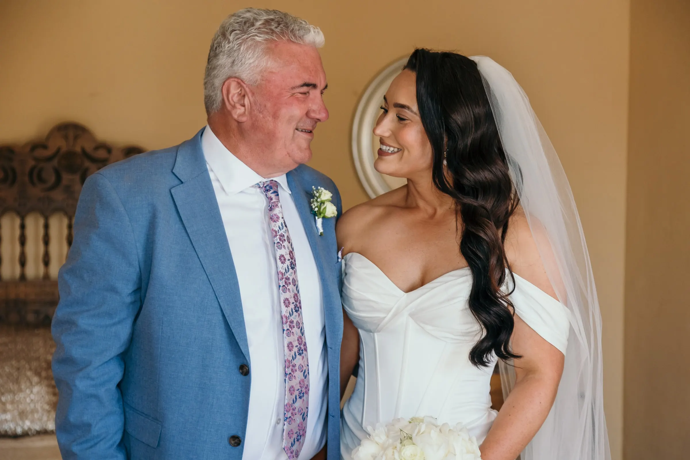 La novia comparte una sonrisa con un hombre de traje azul antes de la ceremonia
