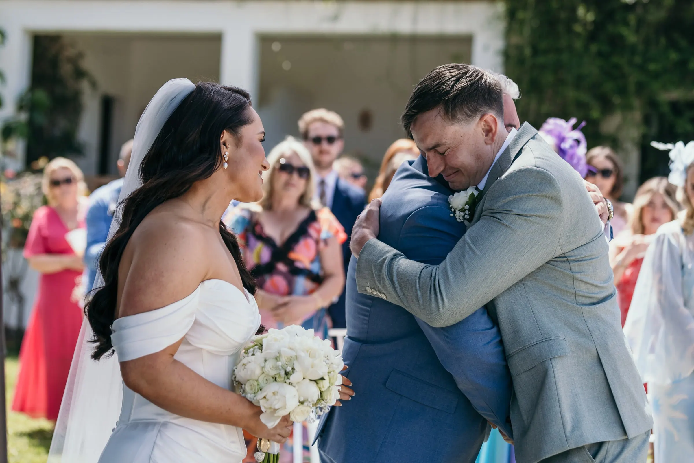 El novio abraza a un hombre de traje azul al final del pasillo