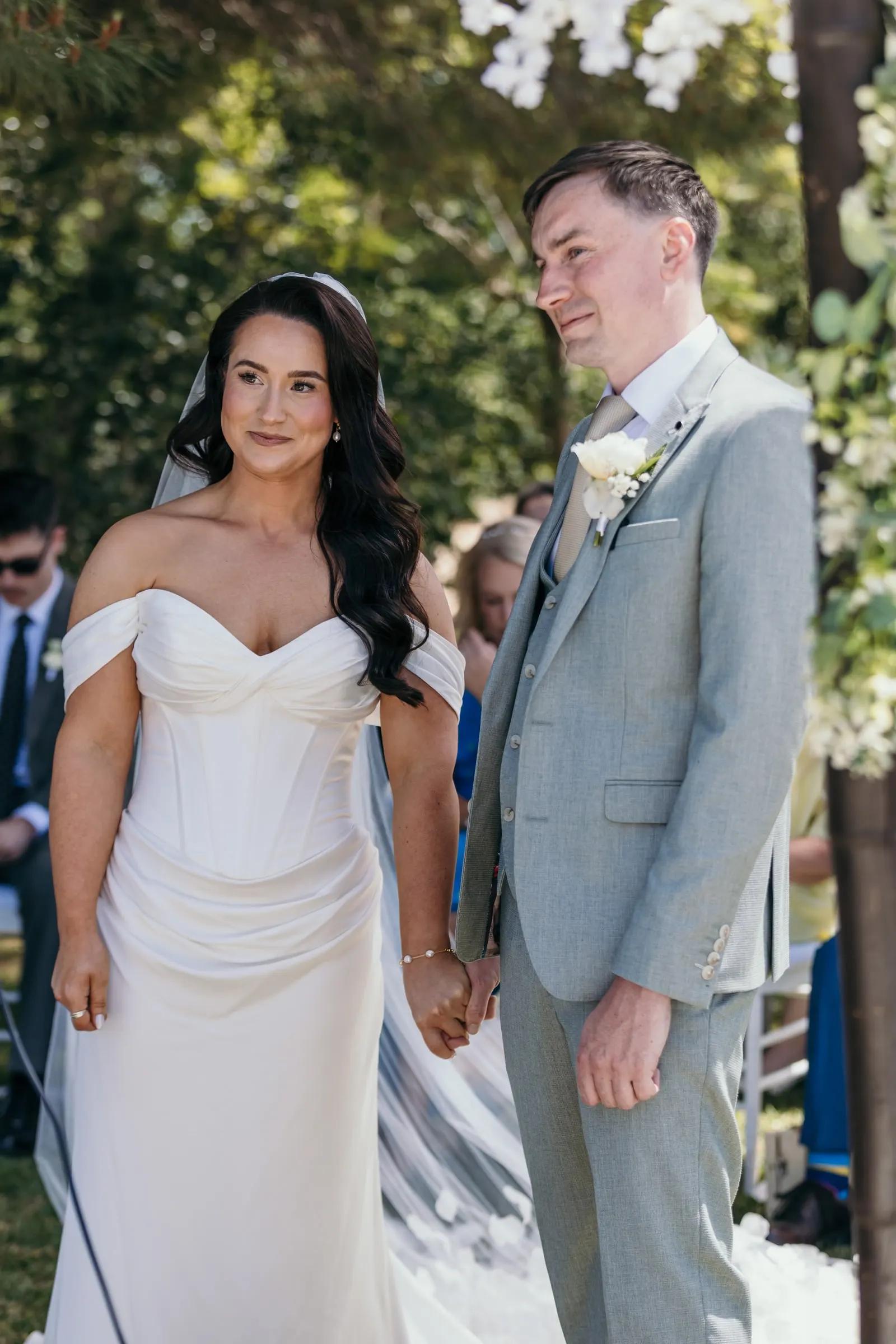 Los novios de la mano frente a los invitados en la ceremonia del jardín