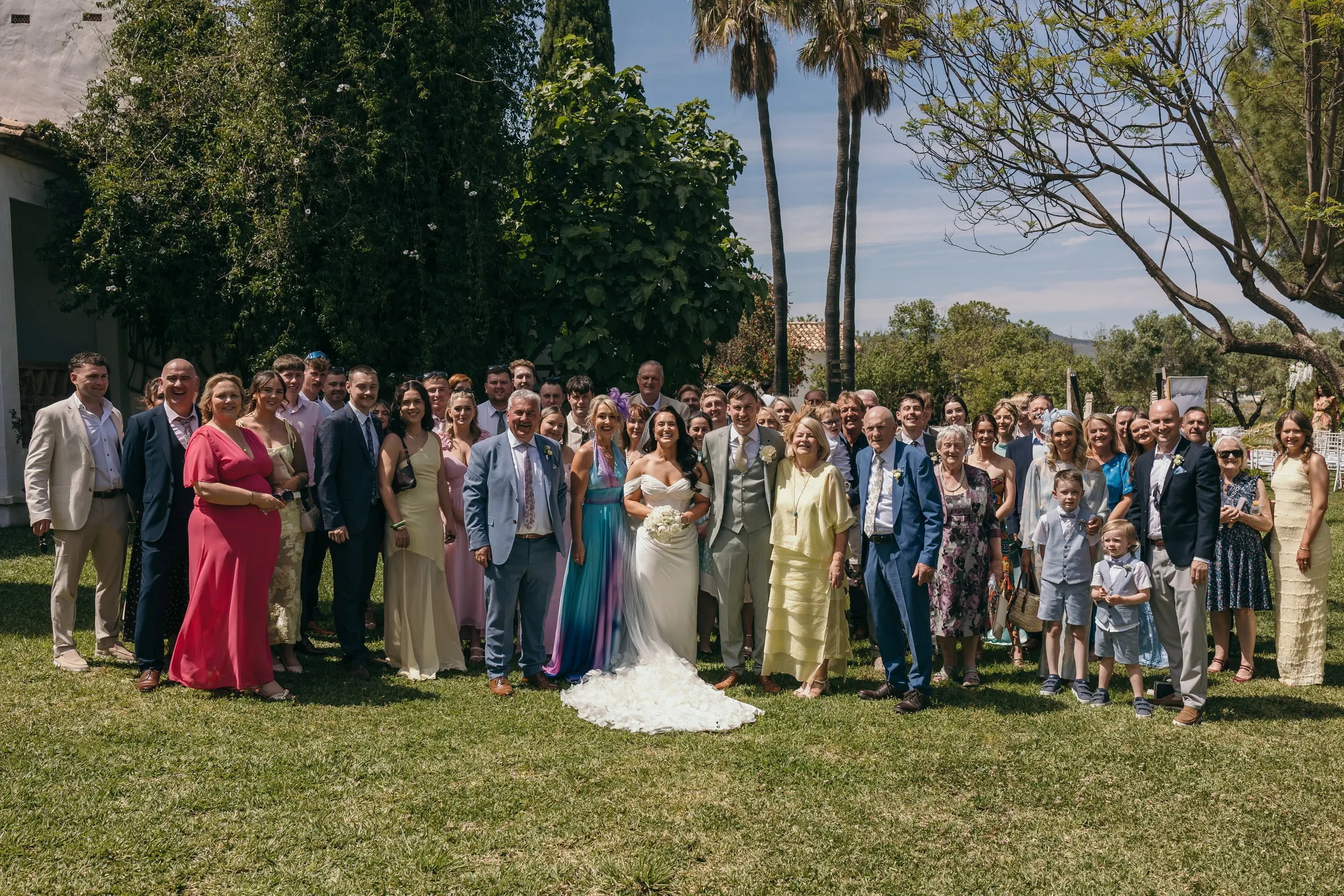 Foto de grupo con todos los invitados en el césped y palmeras detrás, Hacienda San José