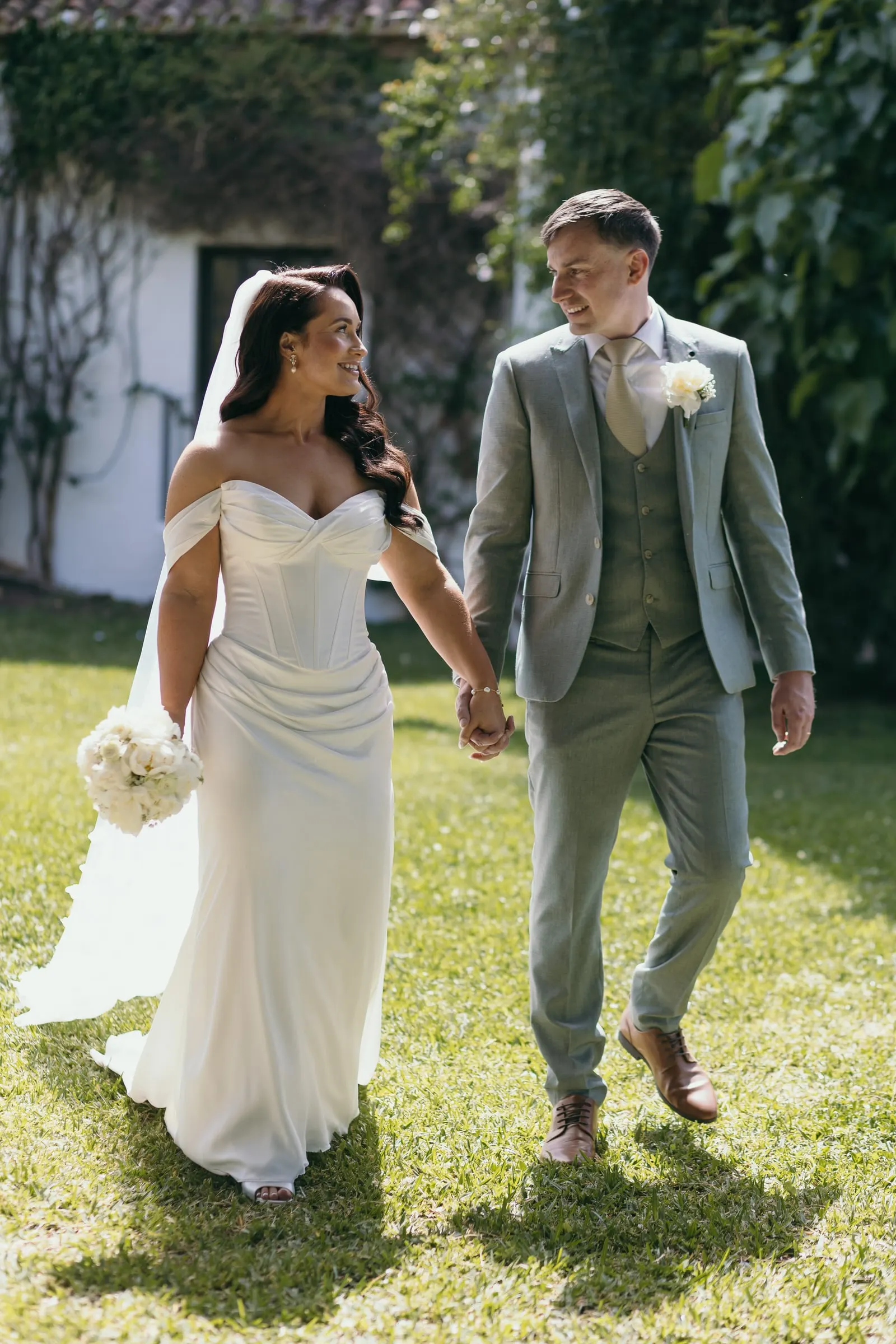 Los novios caminan de la mano por el césped