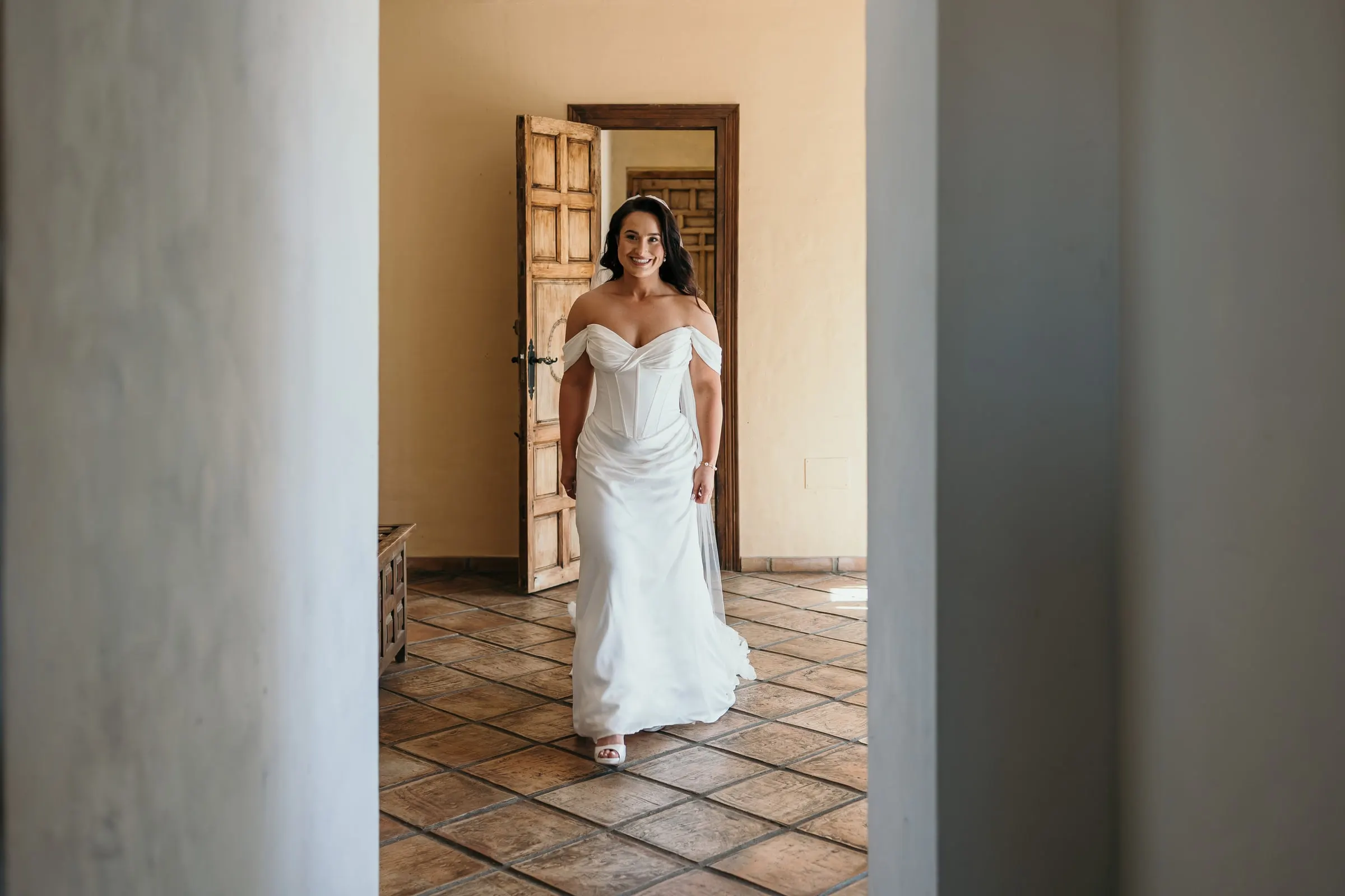 La novia avanza por una sala de baldosas entre columnas blancas
