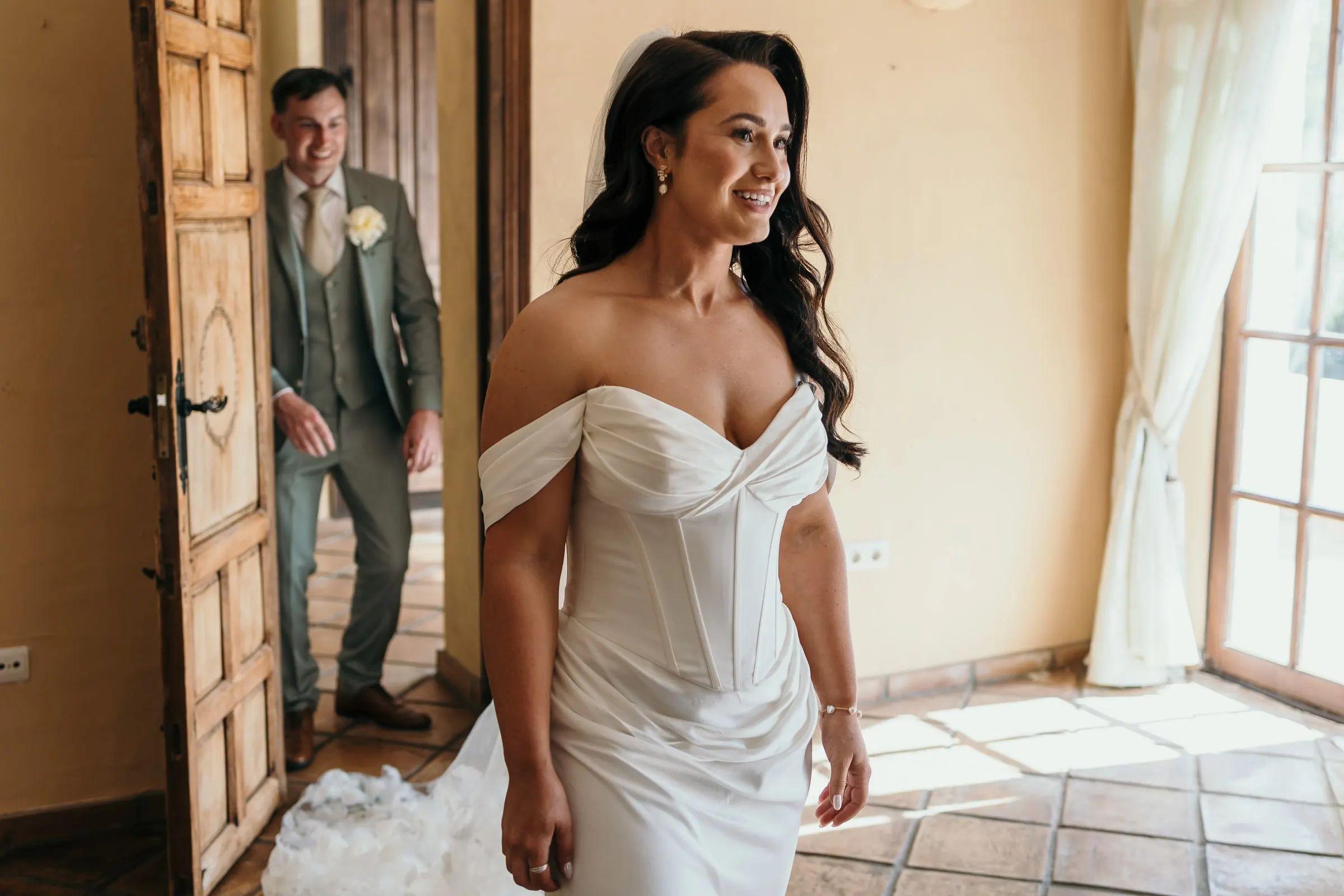 El novio mira a la novia desde una puerta de madera