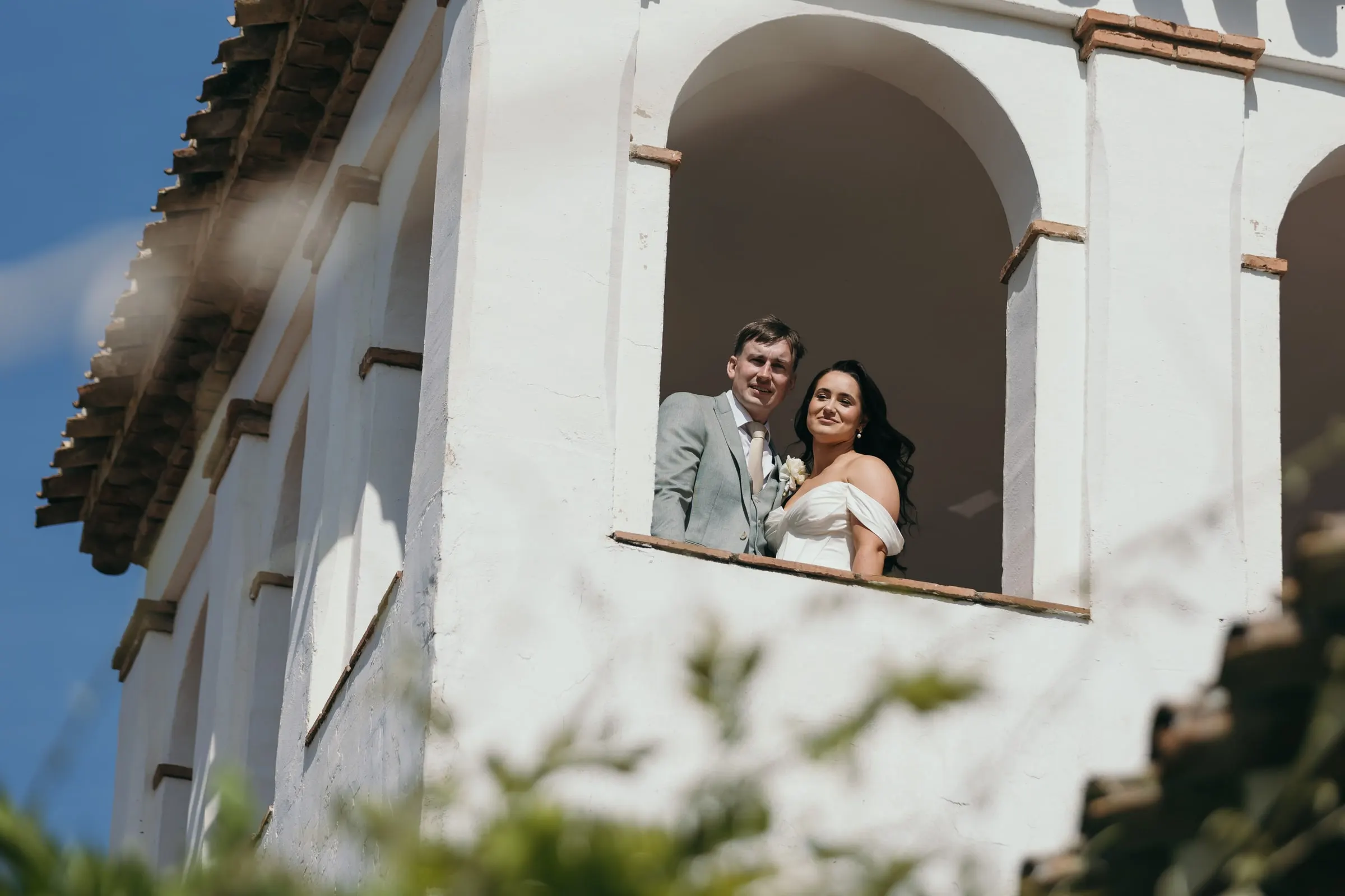 Los novios sonríen asomados a los arcos de la torre
