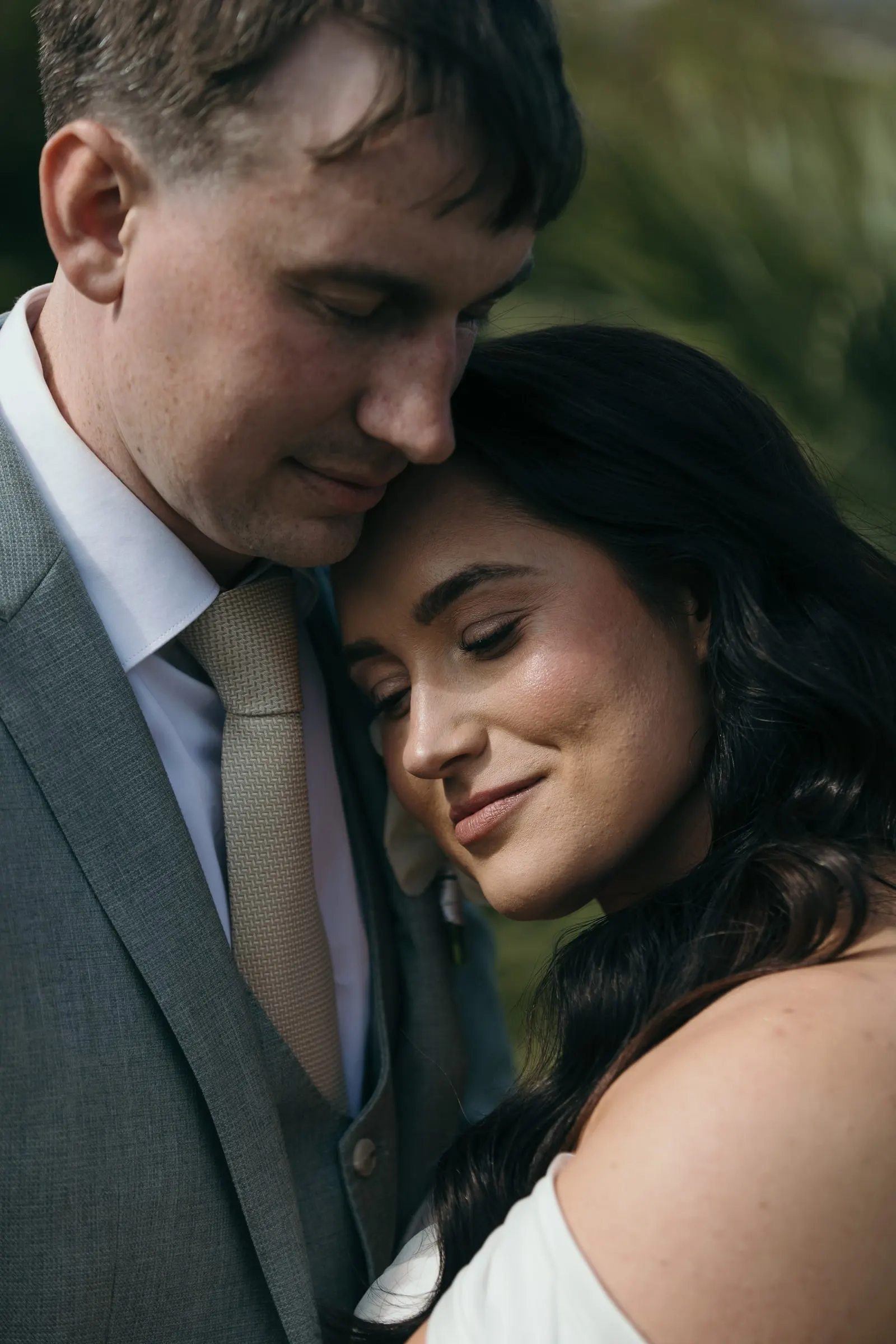 Retrato cercano de la novia apoyando la cabeza en el pecho del novio