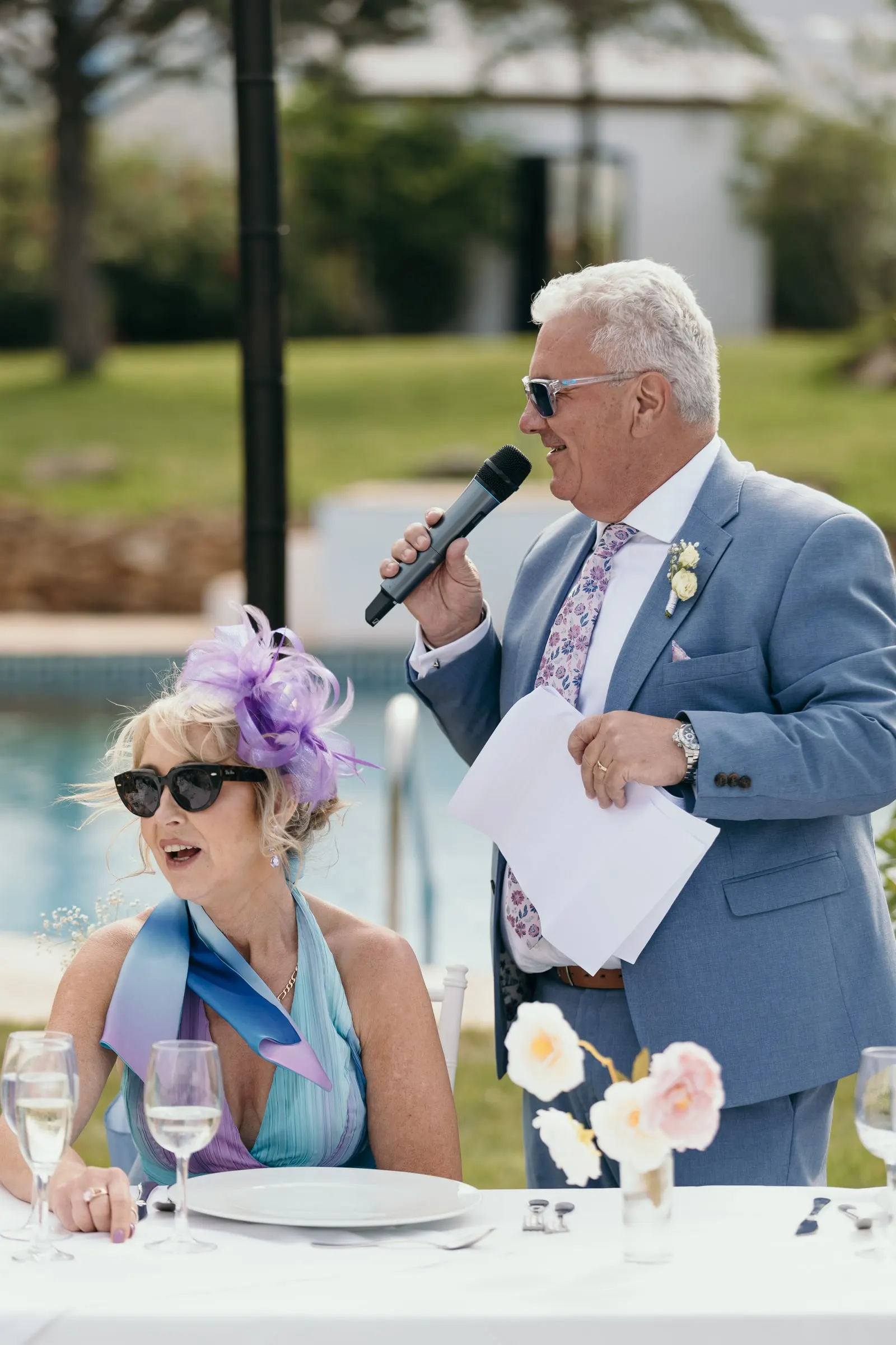 Un hombre de traje azul lee su discurso junto a la piscina