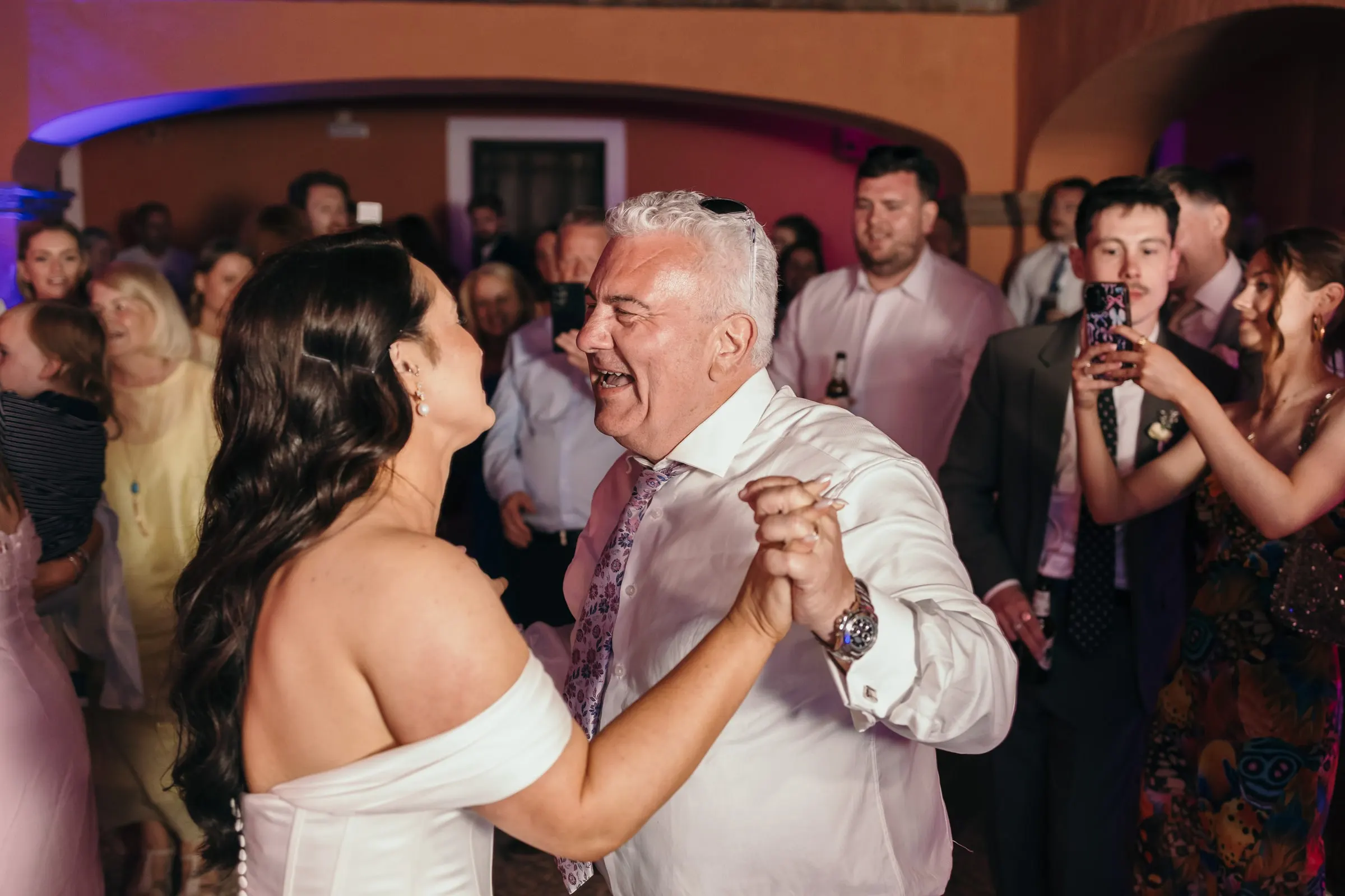 La novia baila con un hombre de camisa blanca en el patio