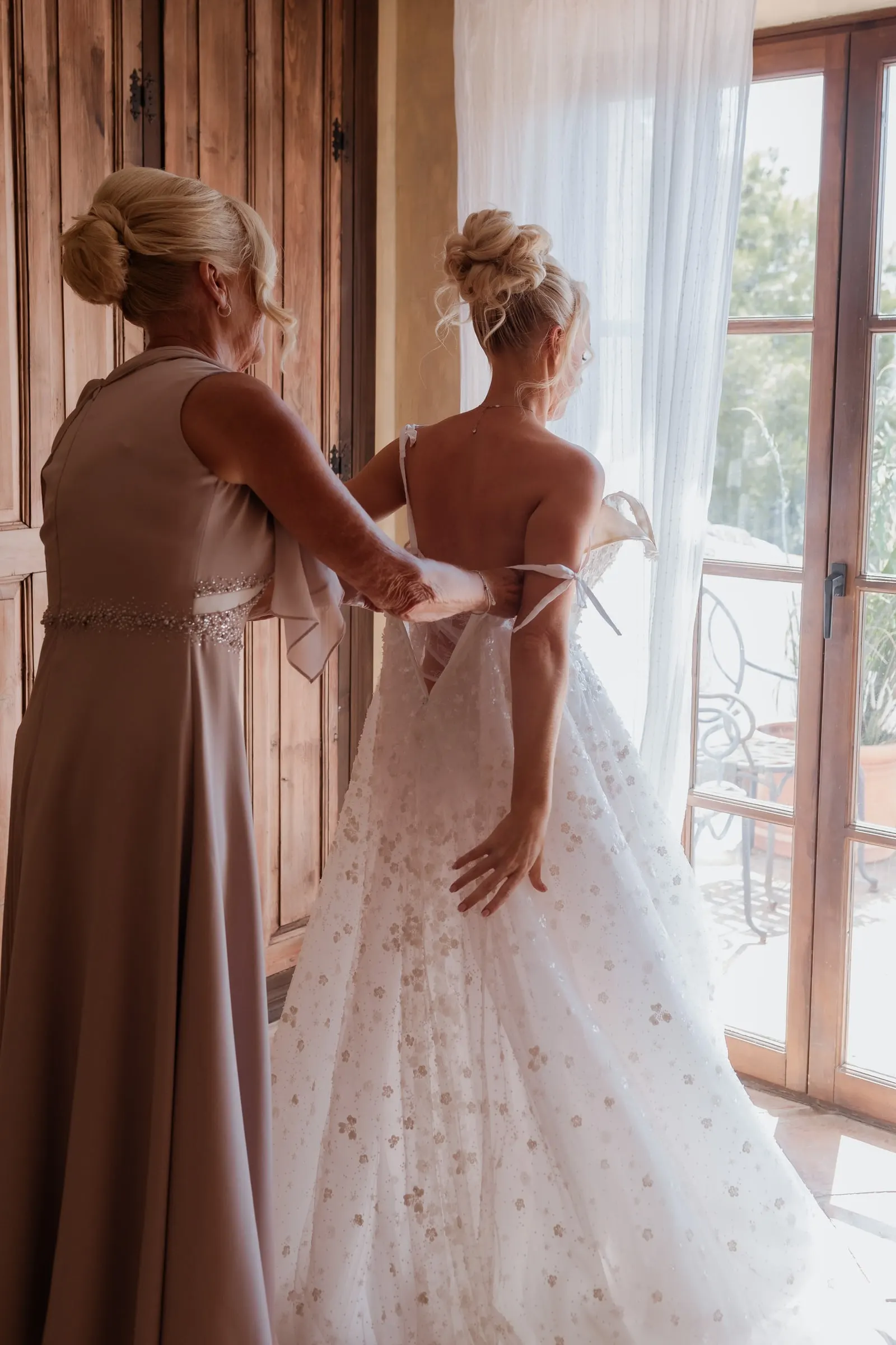 Mother of the bride fastening the back of the wedding dress at Hacienda San José