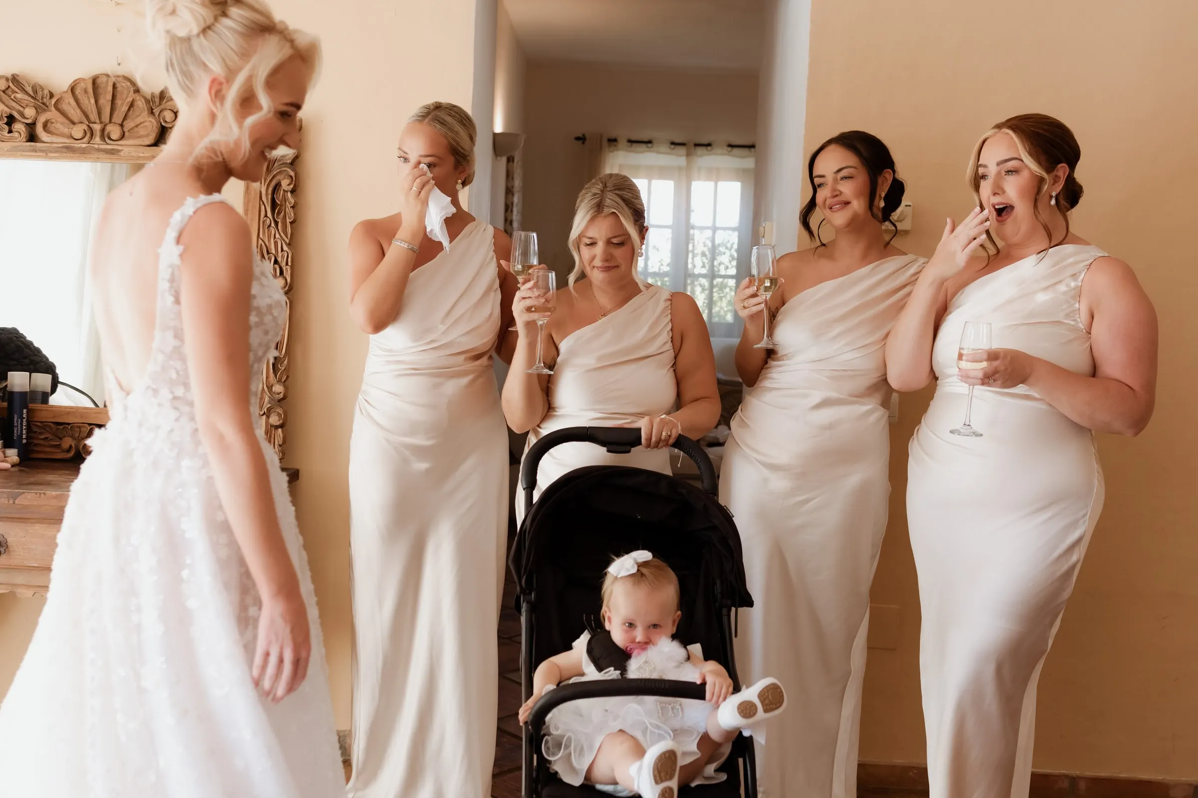 Bridesmaids in champagne satin seeing the bride in her dress for the first time