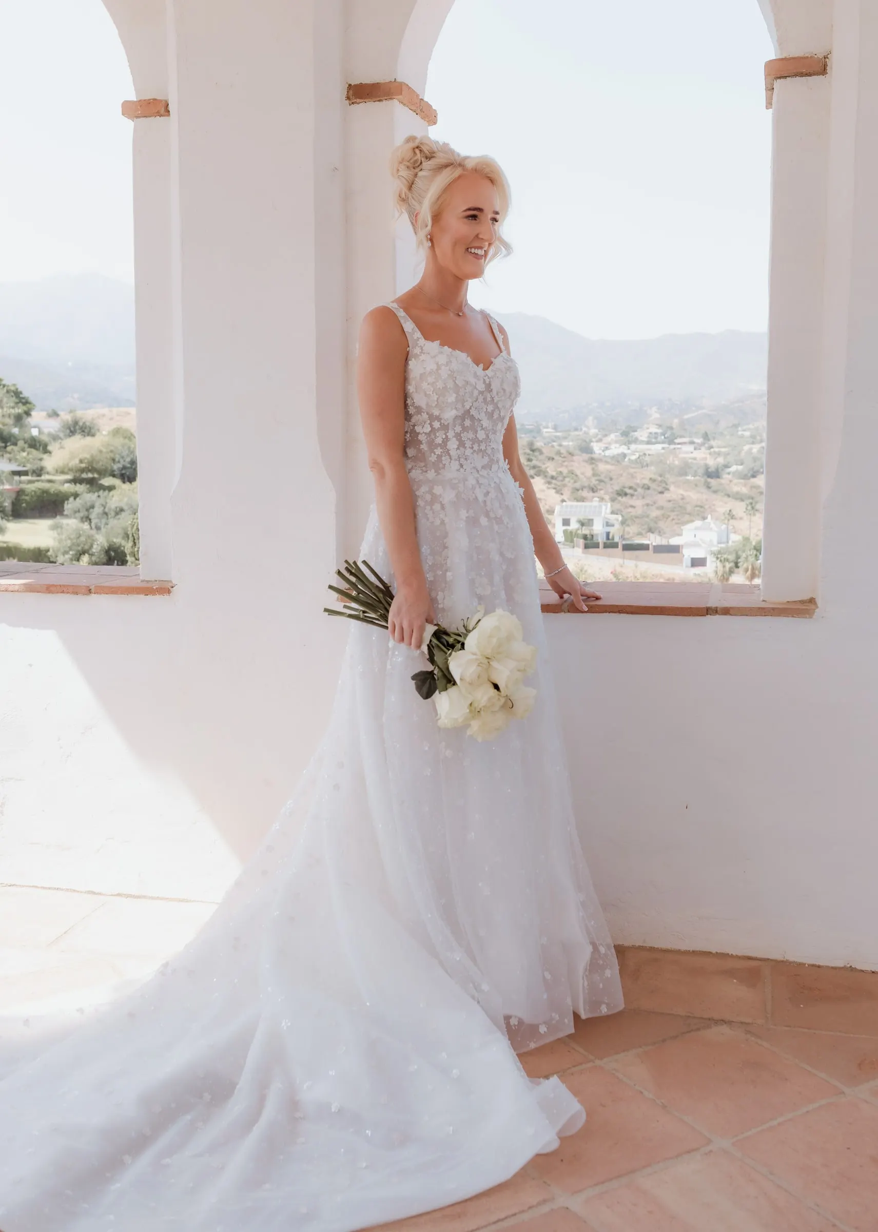 La novia en una ventana en arco con los montes de Mijas al fondo