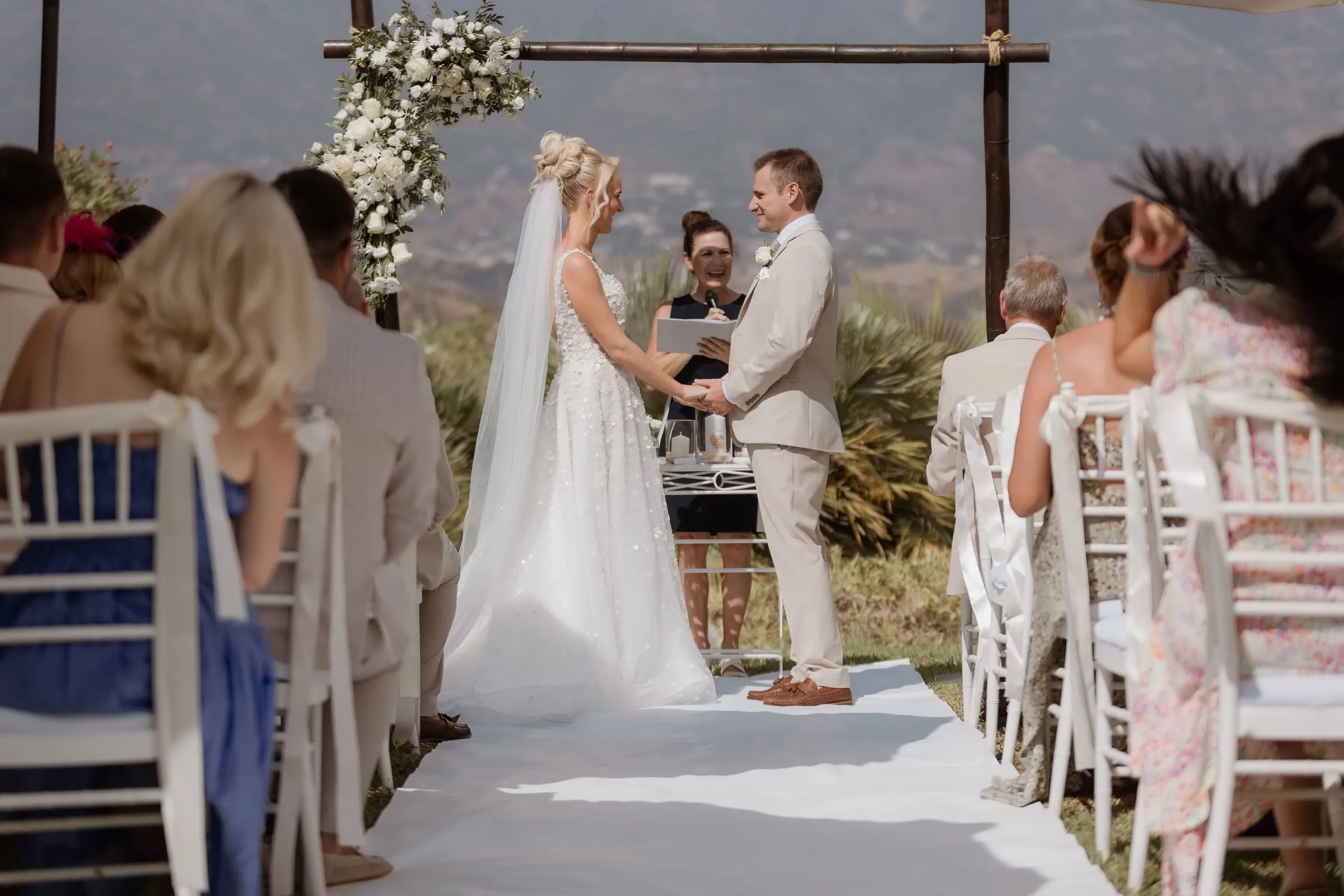 Couple at the flower-decked wooden arch during the garden ceremony at Hacienda San José