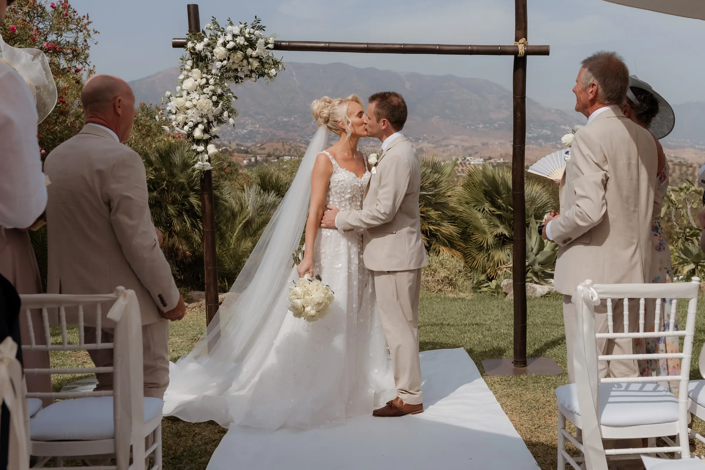 First kiss under the wedding arch with the mountains behind, Mijas
