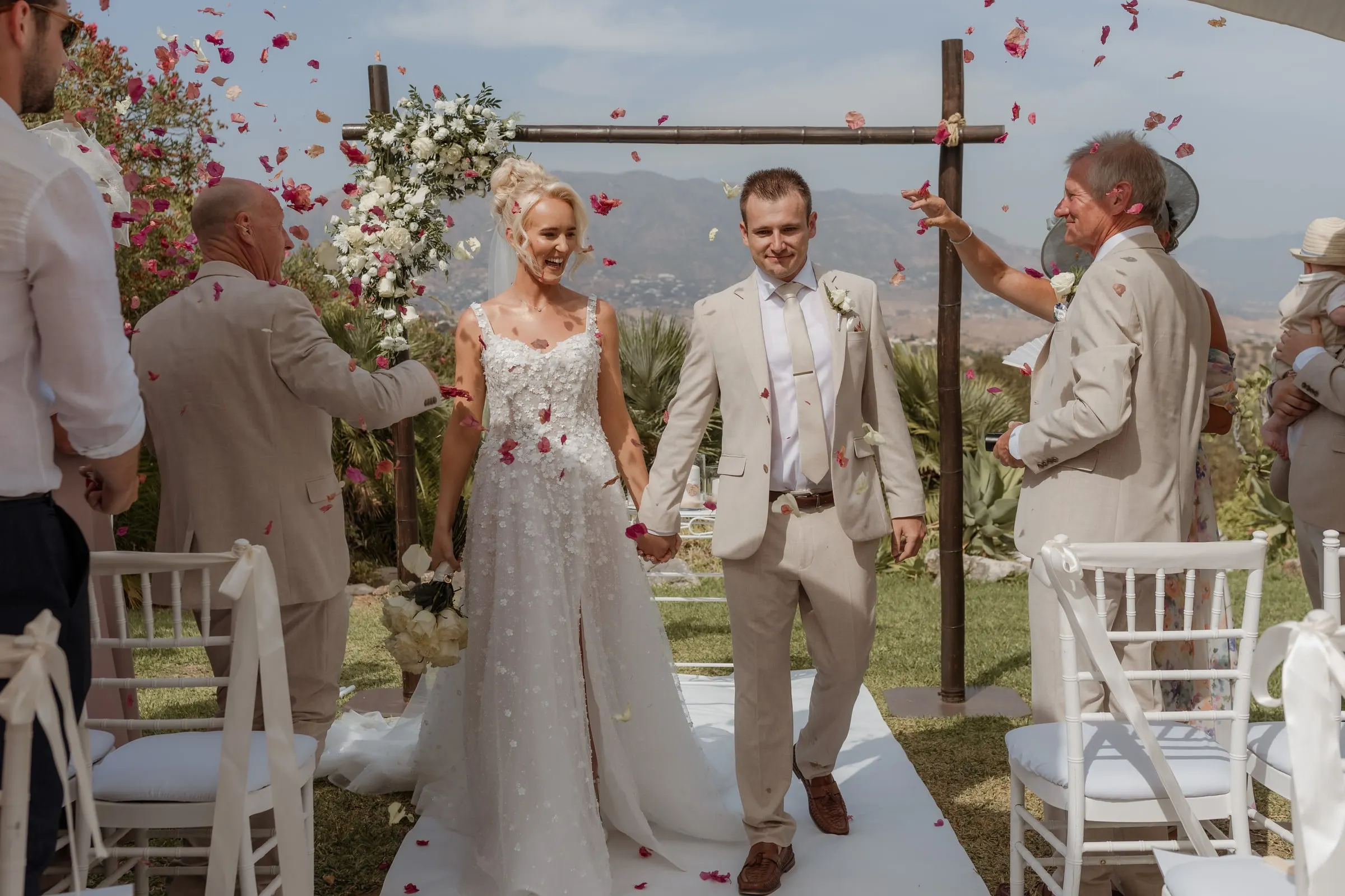 Guests throwing petals as the newlyweds walk back up the aisle at Hacienda San José