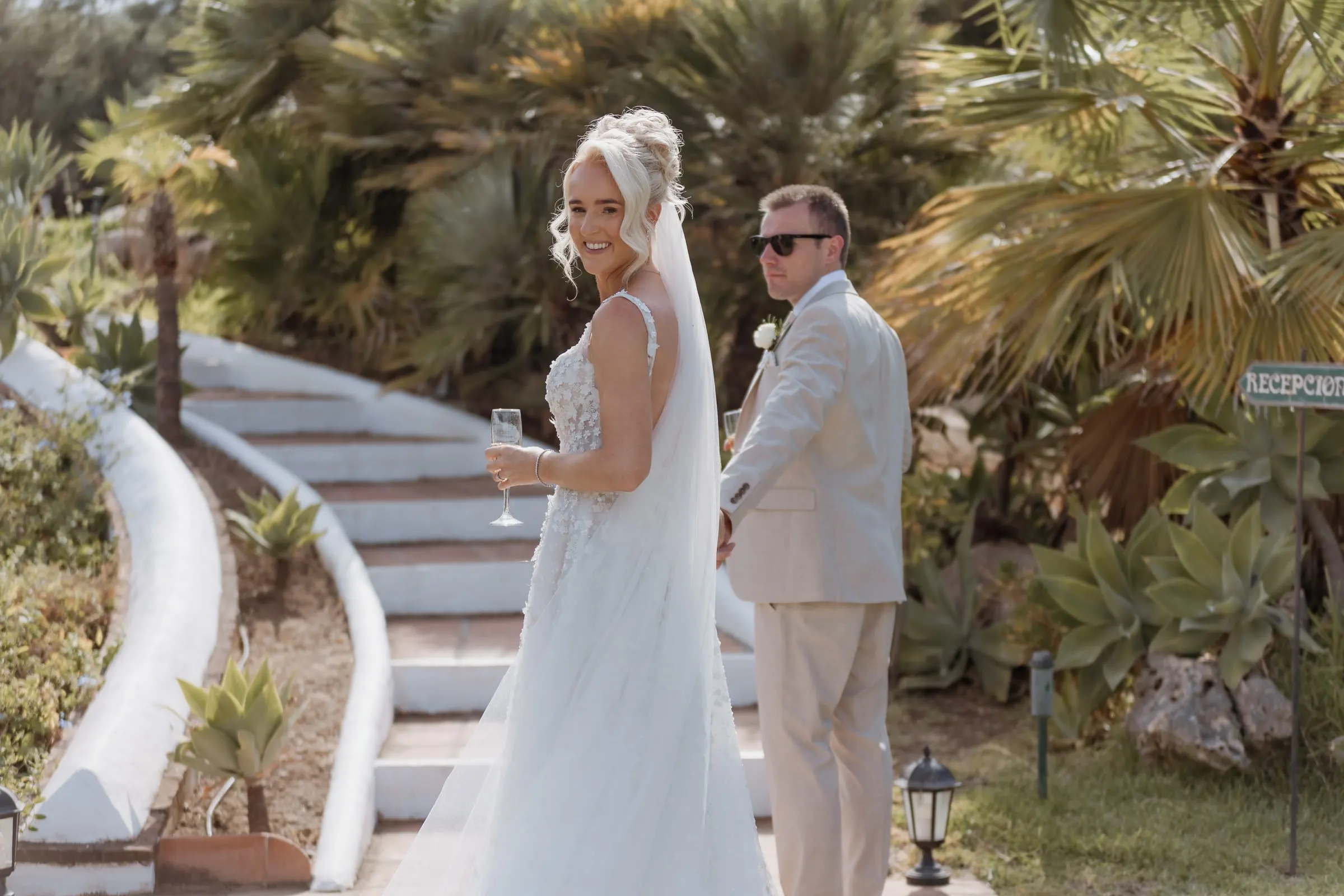 Couple on a curved white staircase among palm trees at Hacienda San José