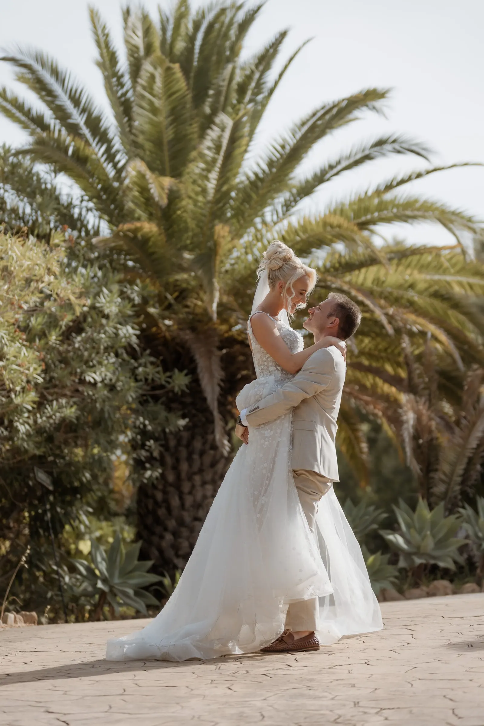 Groom lifting the bride under a palm tree at Hacienda San José