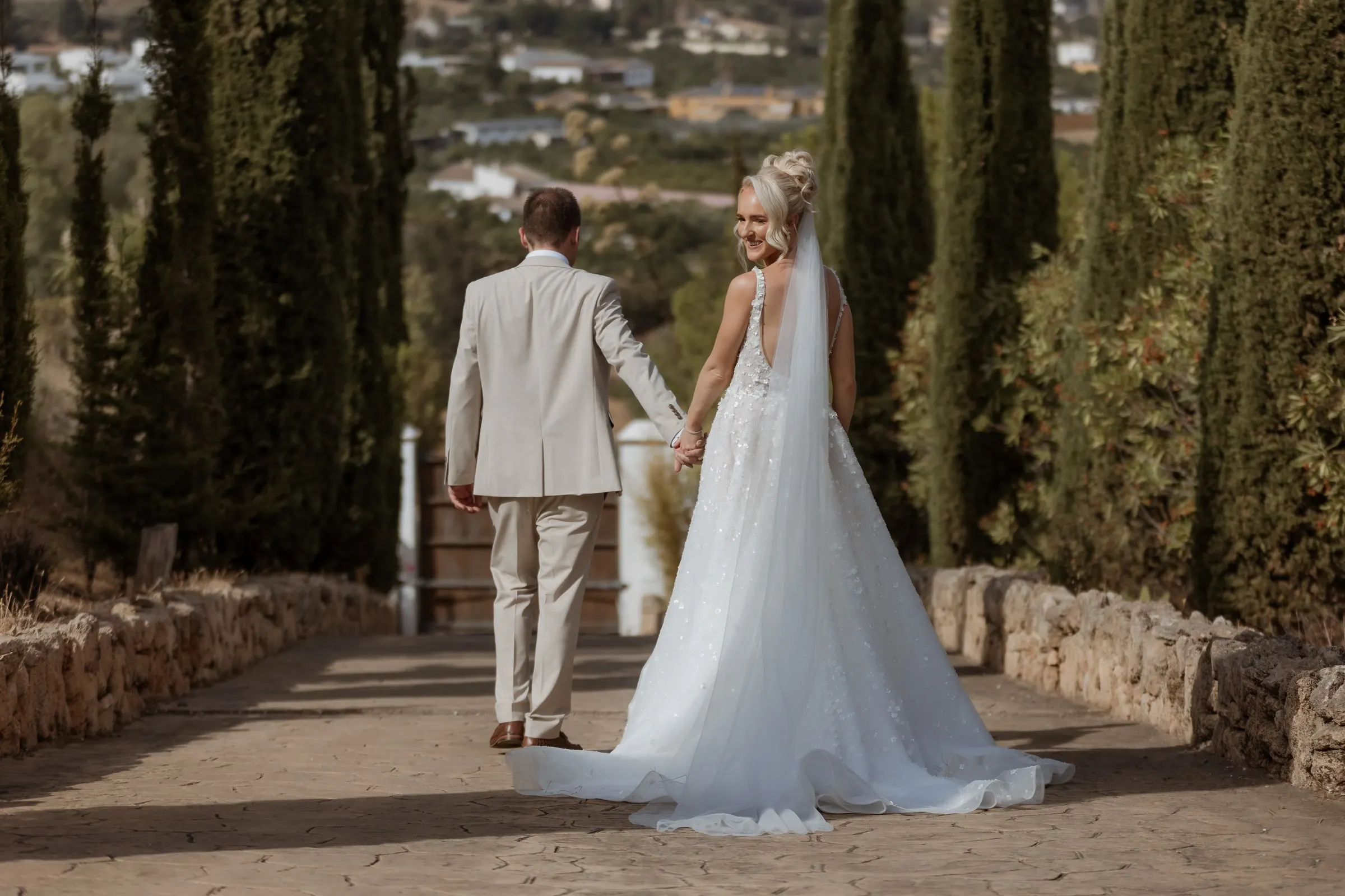 Los novios de la mano por el paseo de cipreses sobre el valle de Mijas
