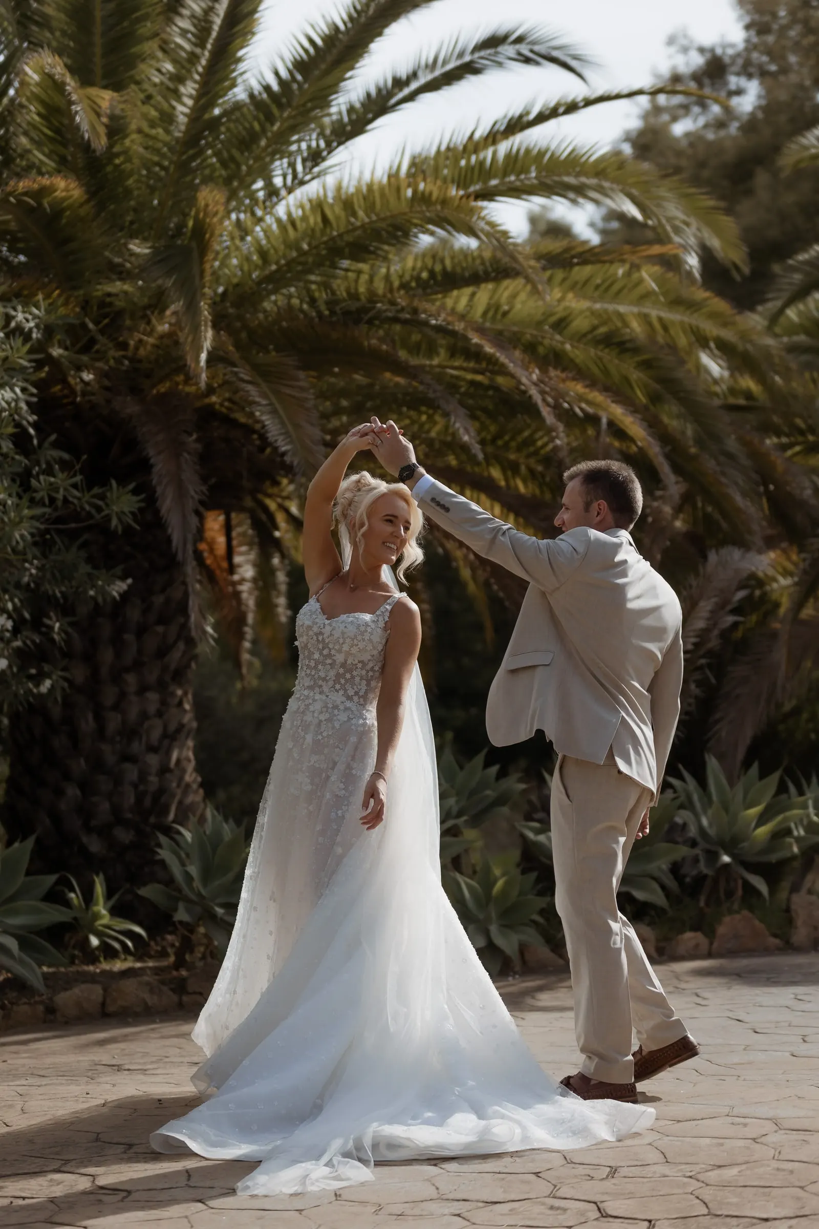 Groom twirling the bride on the terrace under the palms