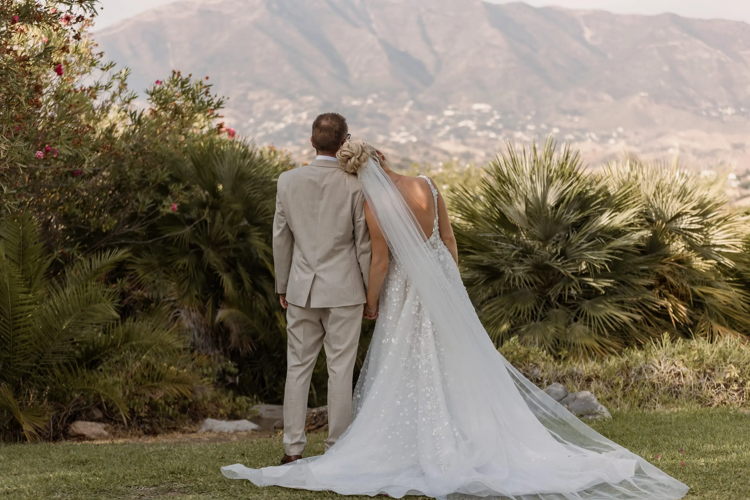 Los novios de espaldas mirando la sierra sobre Mijas