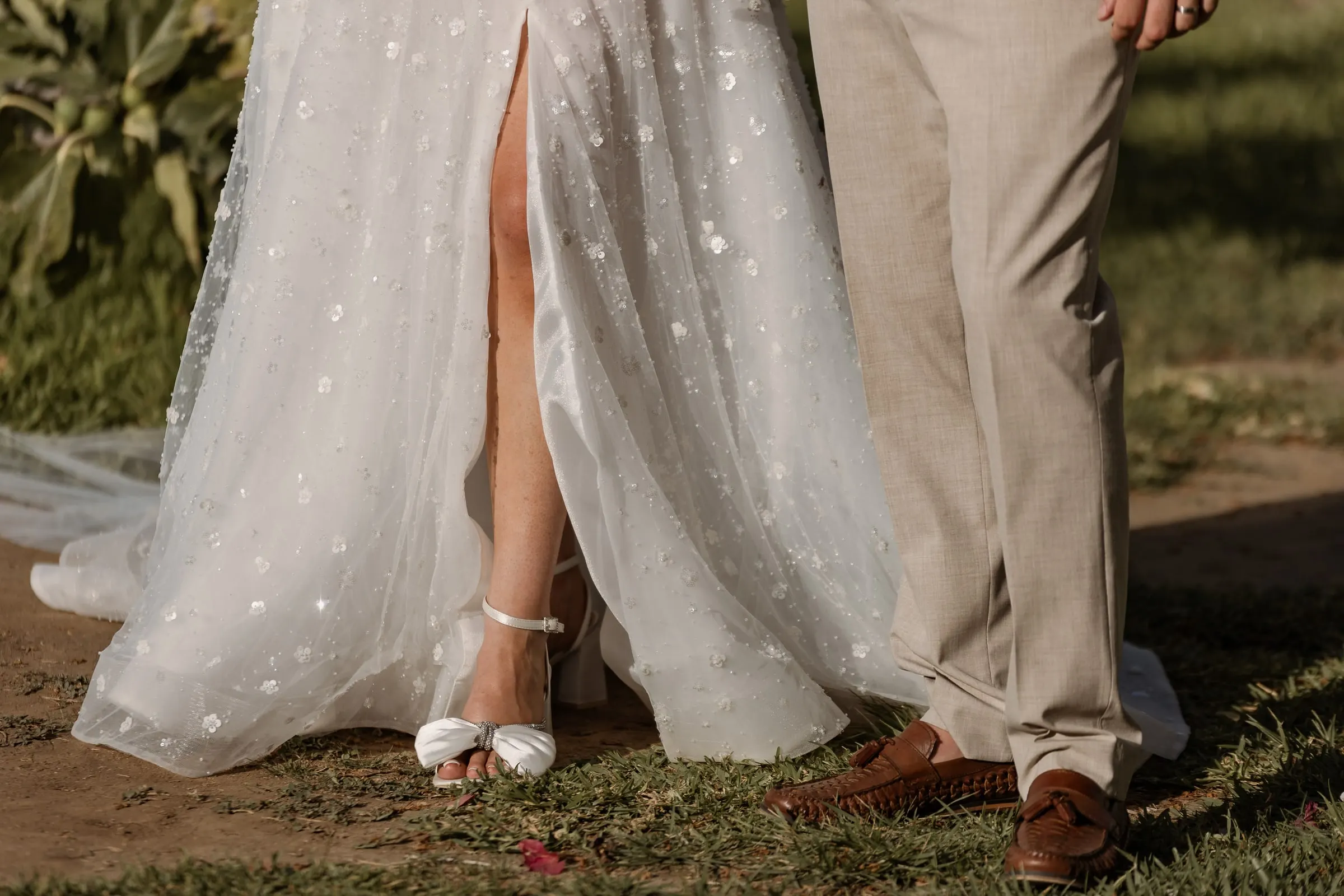 Detail of the beaded wedding dress, the bride's shoes and the groom's suit