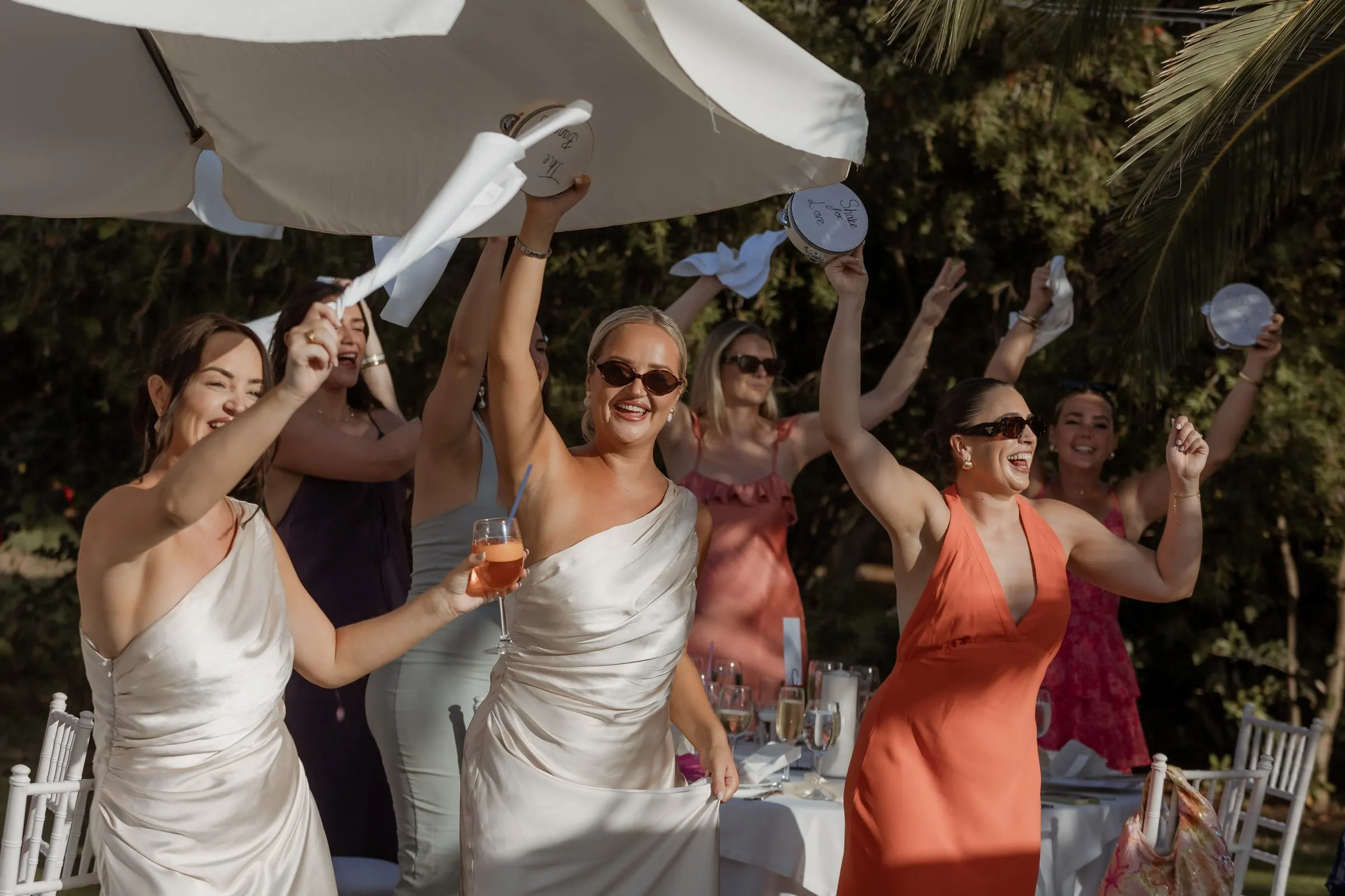 Bridesmaids waving their napkins under the parasols at the reception