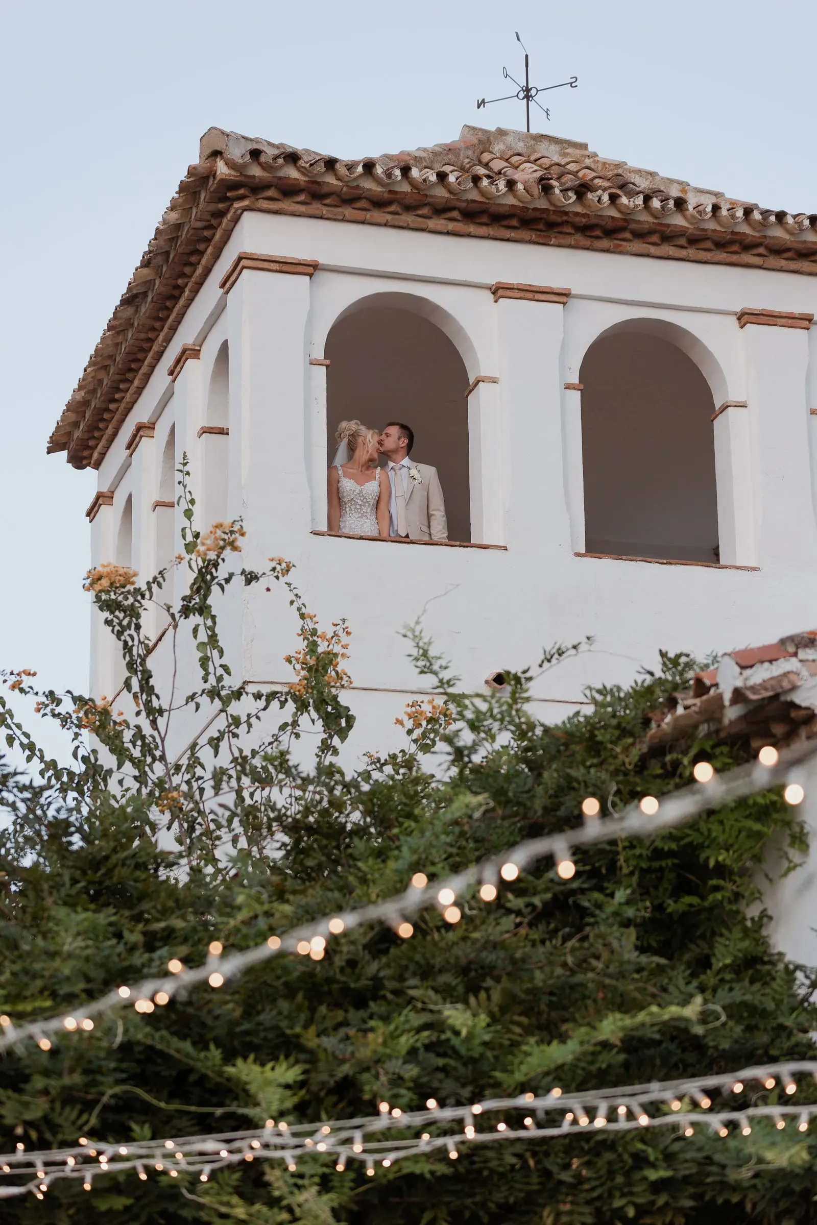 Bride at the tower window above the fairy lights at Hacienda San José