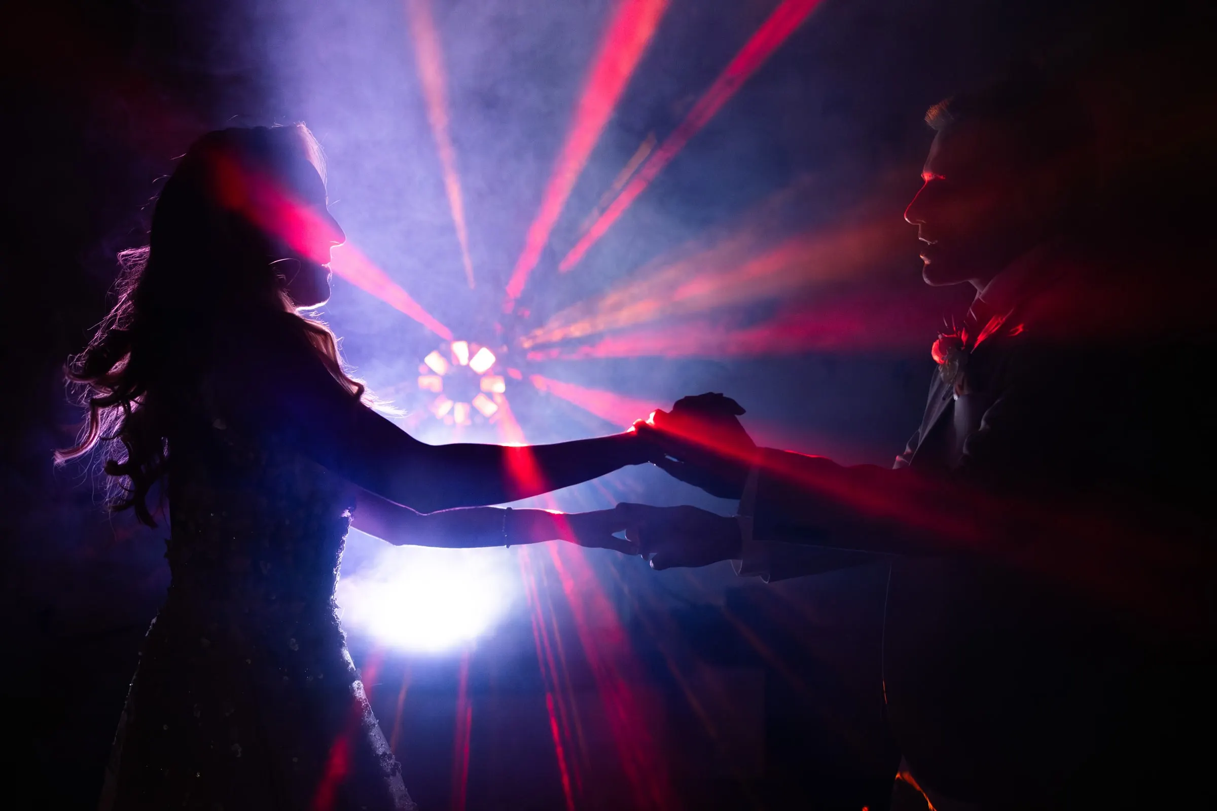Couple dancing in silhouette among red laser lights