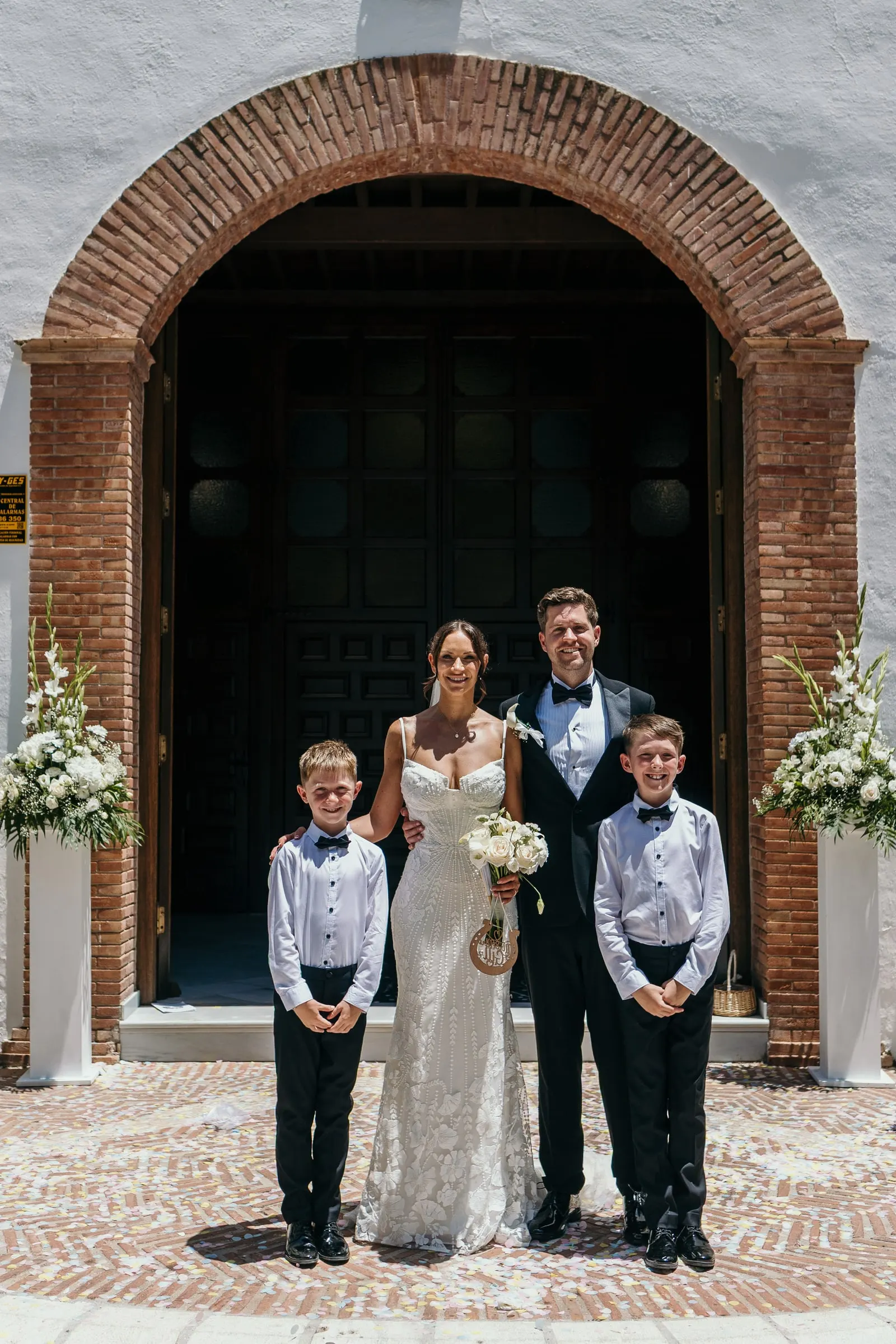 Newlyweds with the pageboys under the brick arch of the church door, Mijas