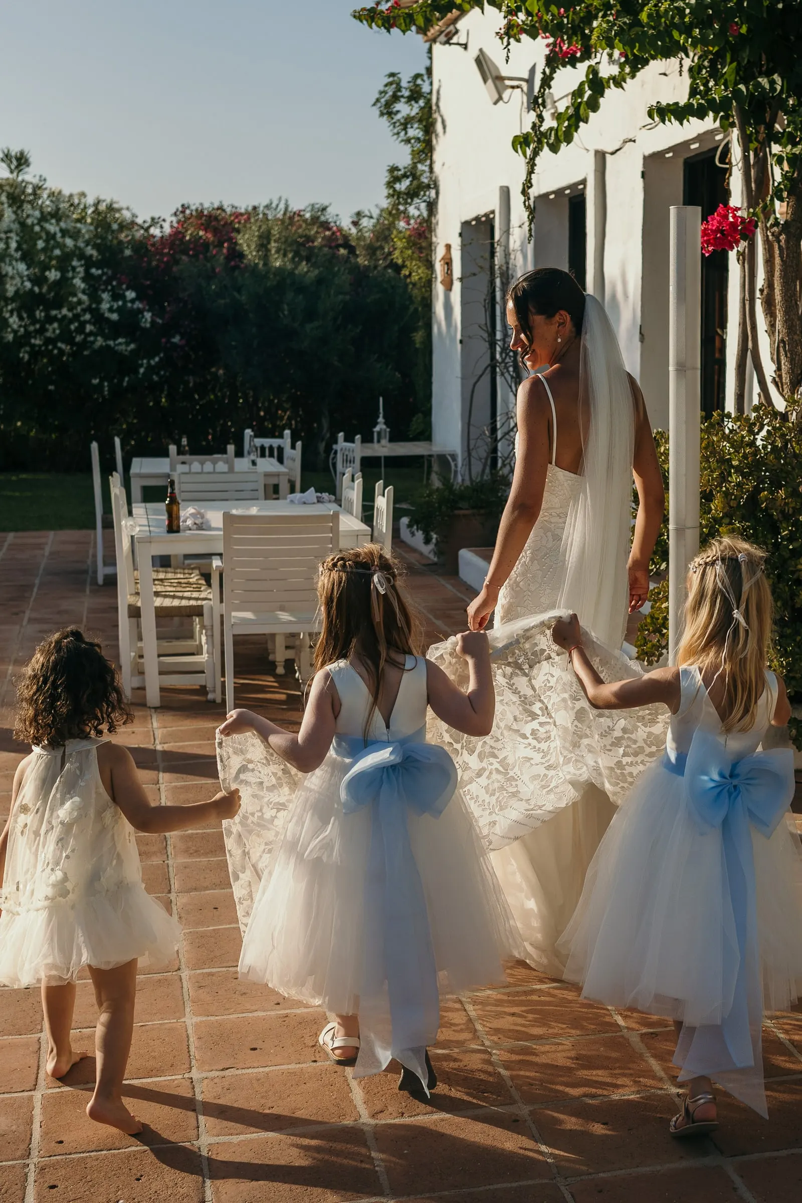 Flower girls in pale blue running across the hacienda terrace