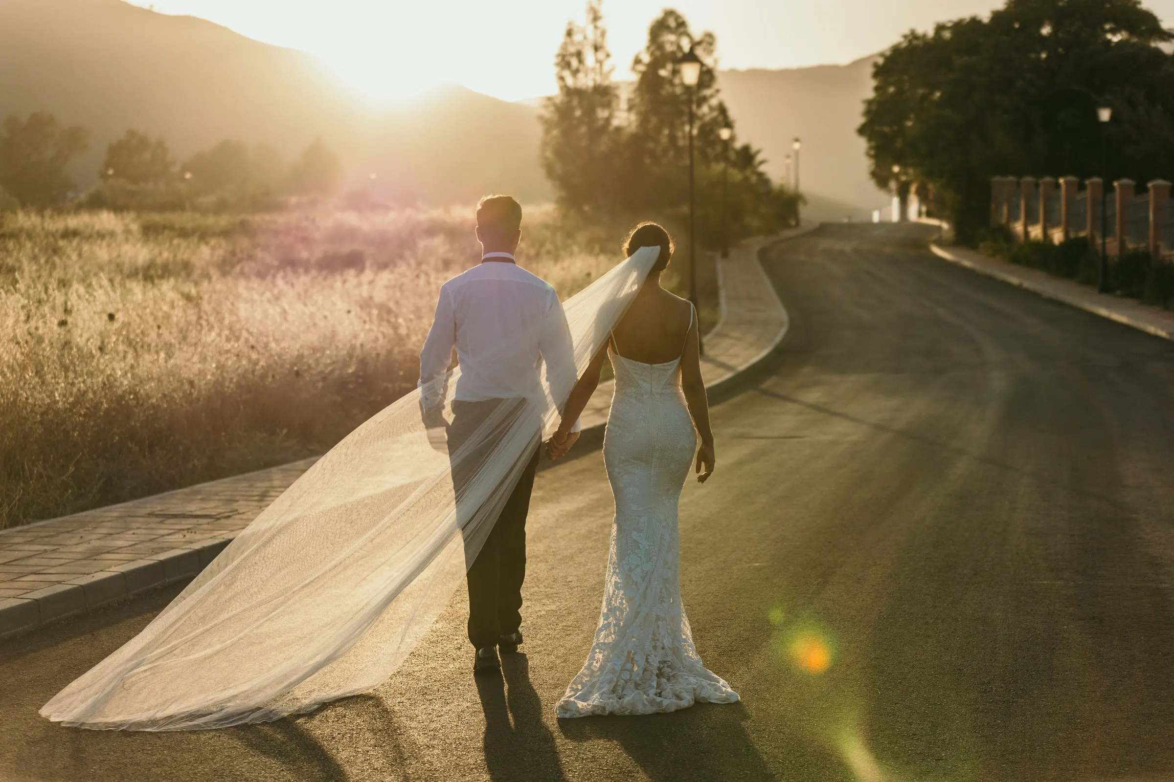 Los novios caminan de la mano por un camino rural en la hora dorada, Mijas