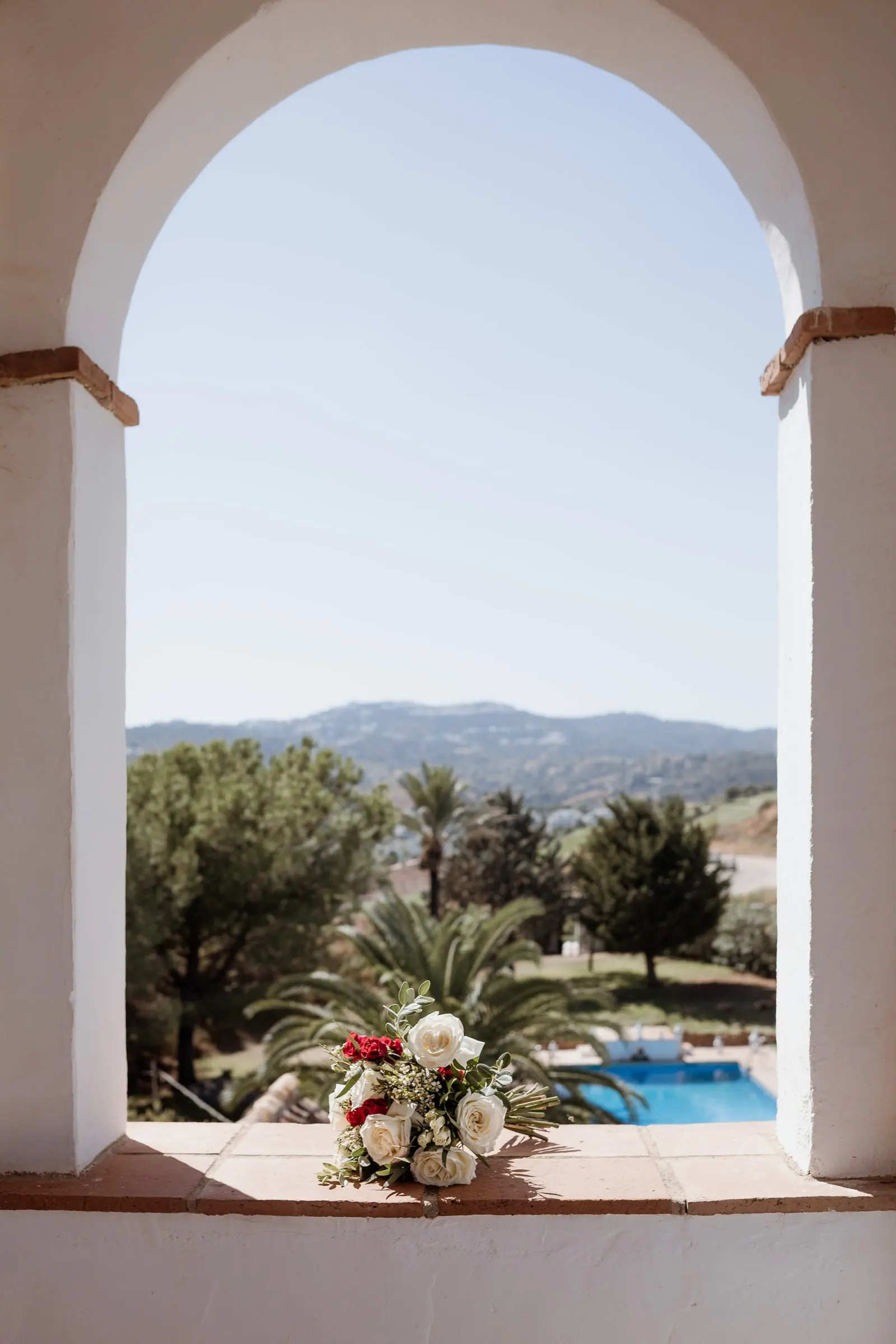 El ramo de novia en una ventana en arco encalada con vistas a la piscina y la sierra, Hacienda San José, Mijas