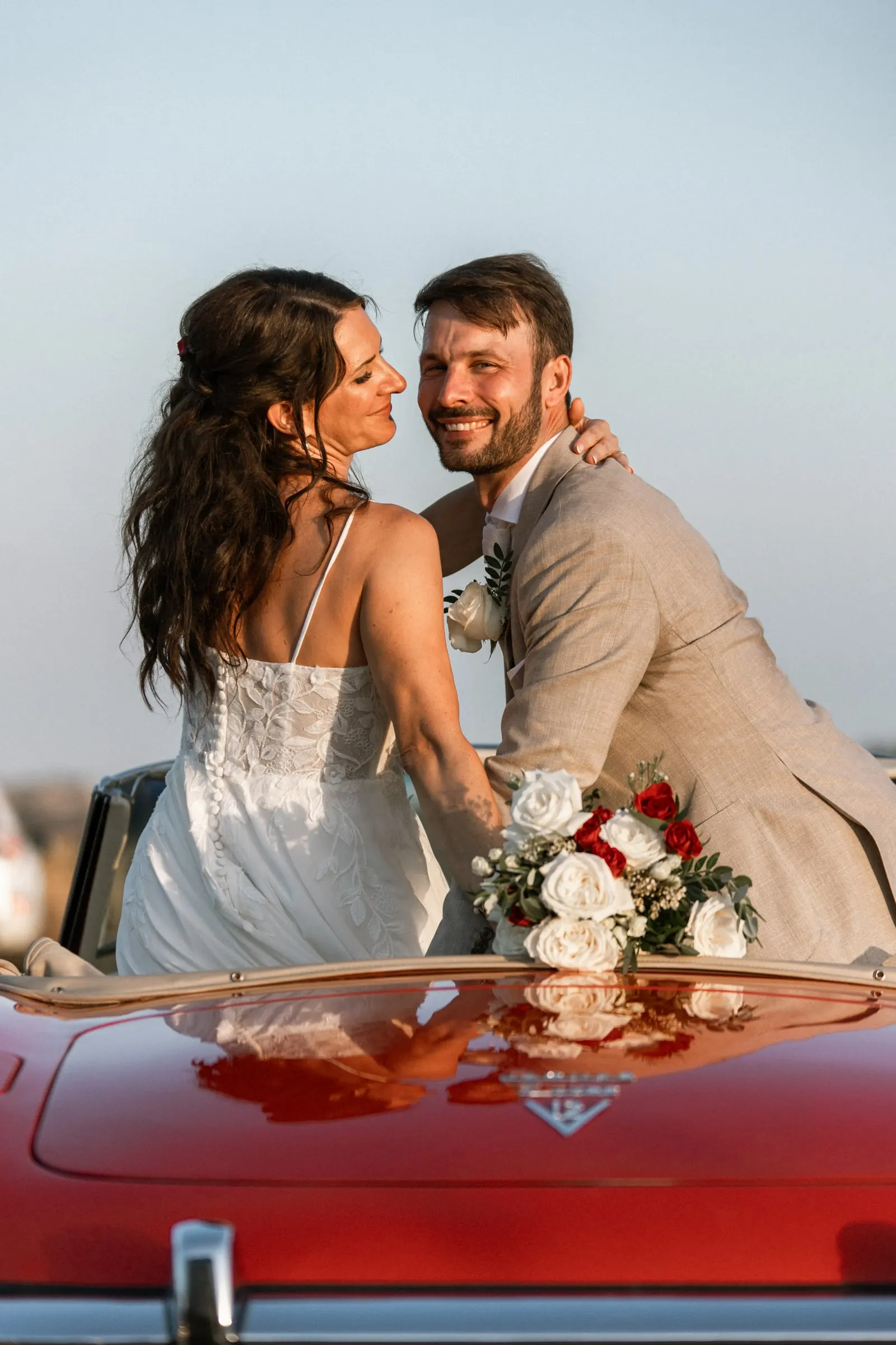 Los novios se sonríen sentados en la parte trasera de un descapotable rojo antiguo, Hacienda San José, Mijas