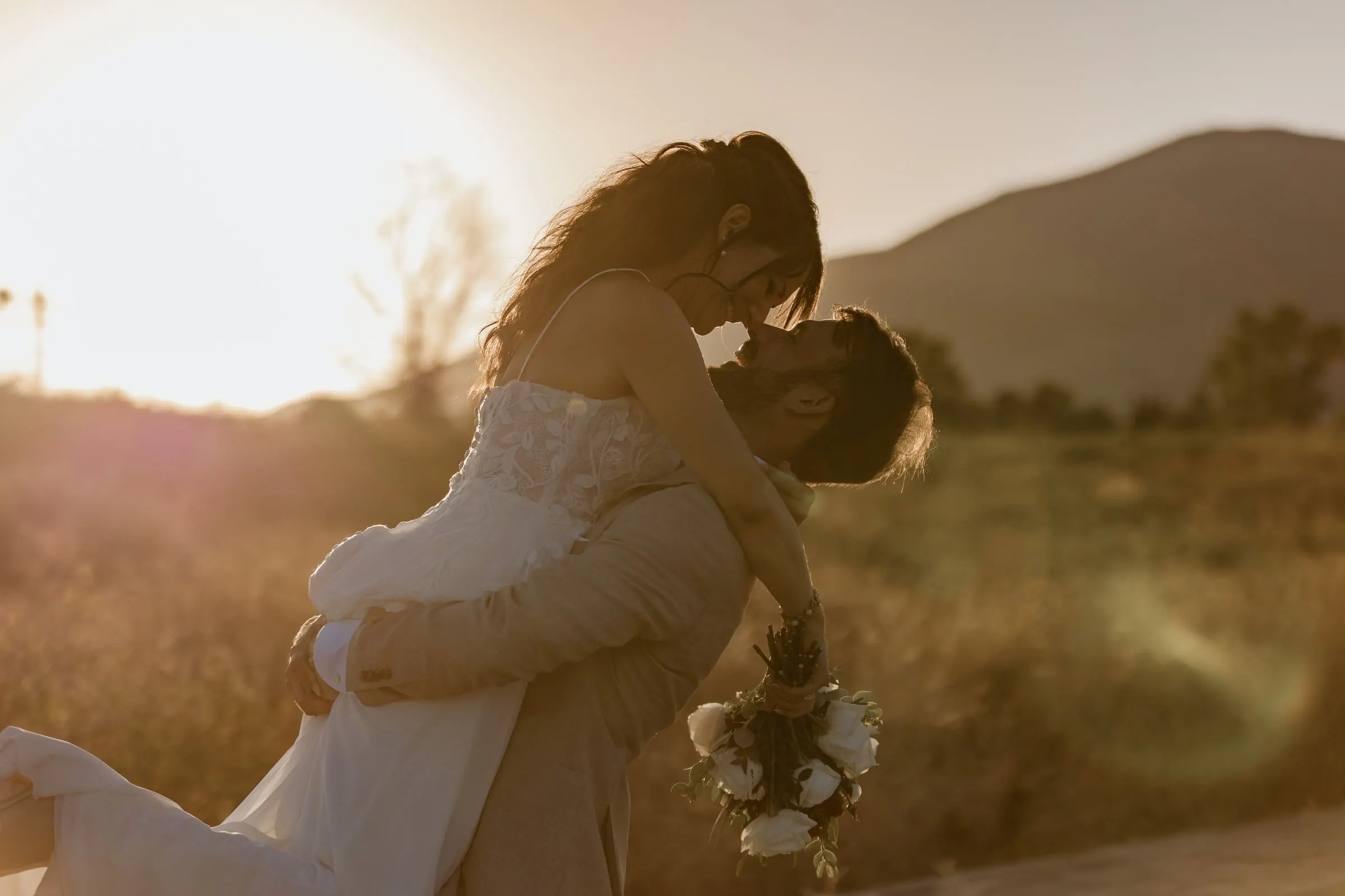 El novio levanta a la novia y la besa en un campo dorado al atardecer, Hacienda San José, Mijas