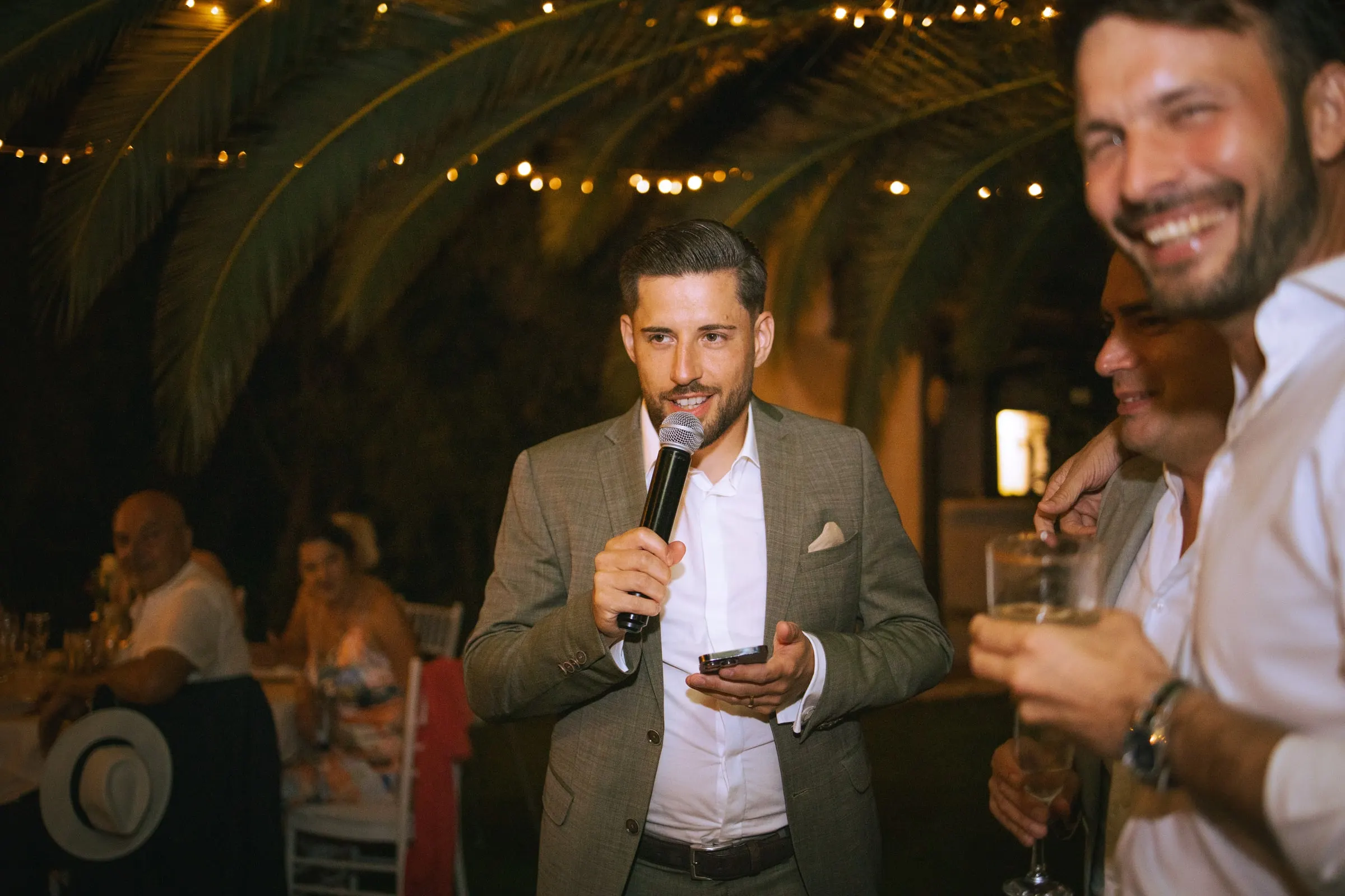 Un invitado con micrófono hace un brindis bajo palmeras y guirnaldas de luces, Hacienda San José, Mijas