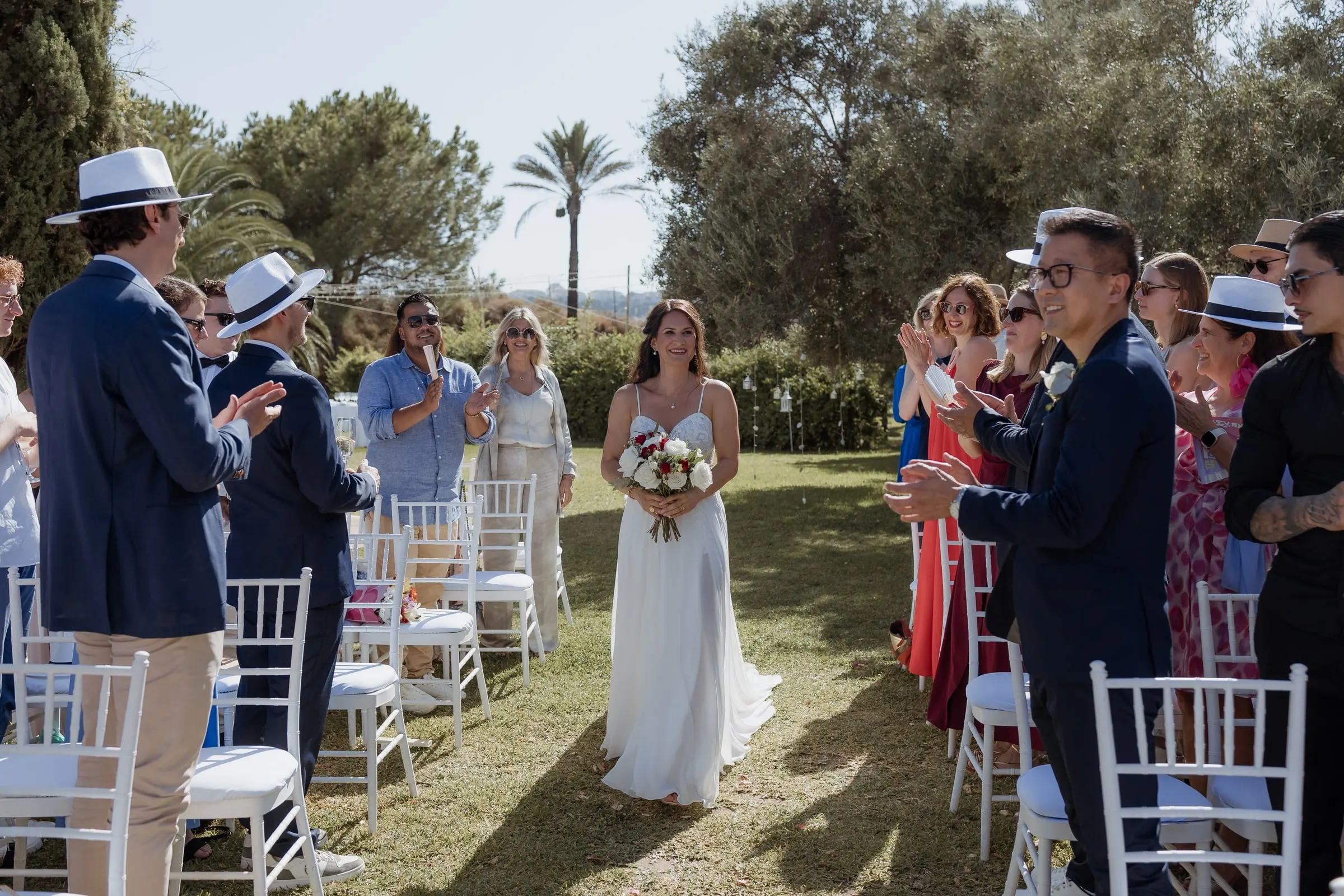 La novia recorre sola el pasillo entre filas de invitados en pie, Hacienda San José, Mijas