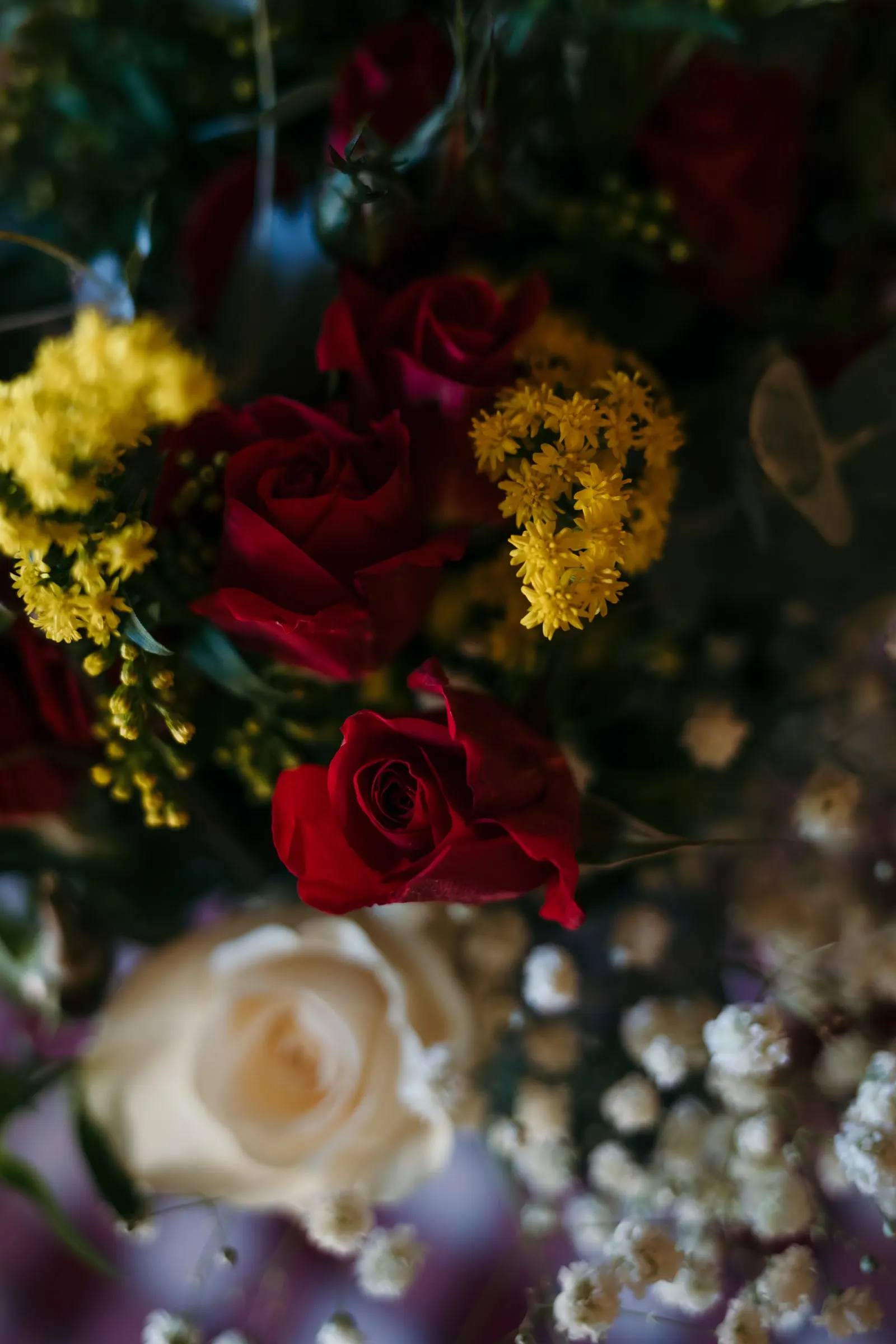 Detalle de rosas rojas y blancas con flores silvestres amarillas en un centro floral, Hacienda San José, Mijas