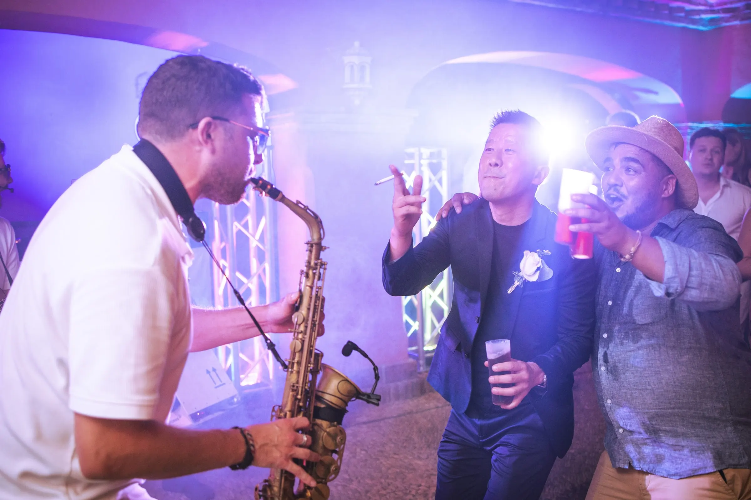 Un saxofonista toca mientras los invitados bailan con luz morada en la fiesta, Hacienda San José, Mijas