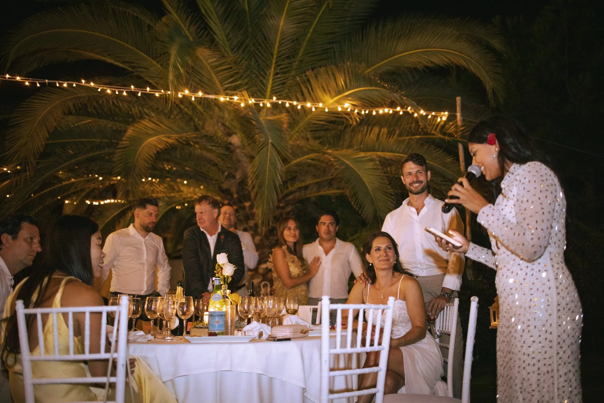 Una invitada con vestido de lentejuelas da un discurso de noche ante su mesa, Hacienda San José, Mijas