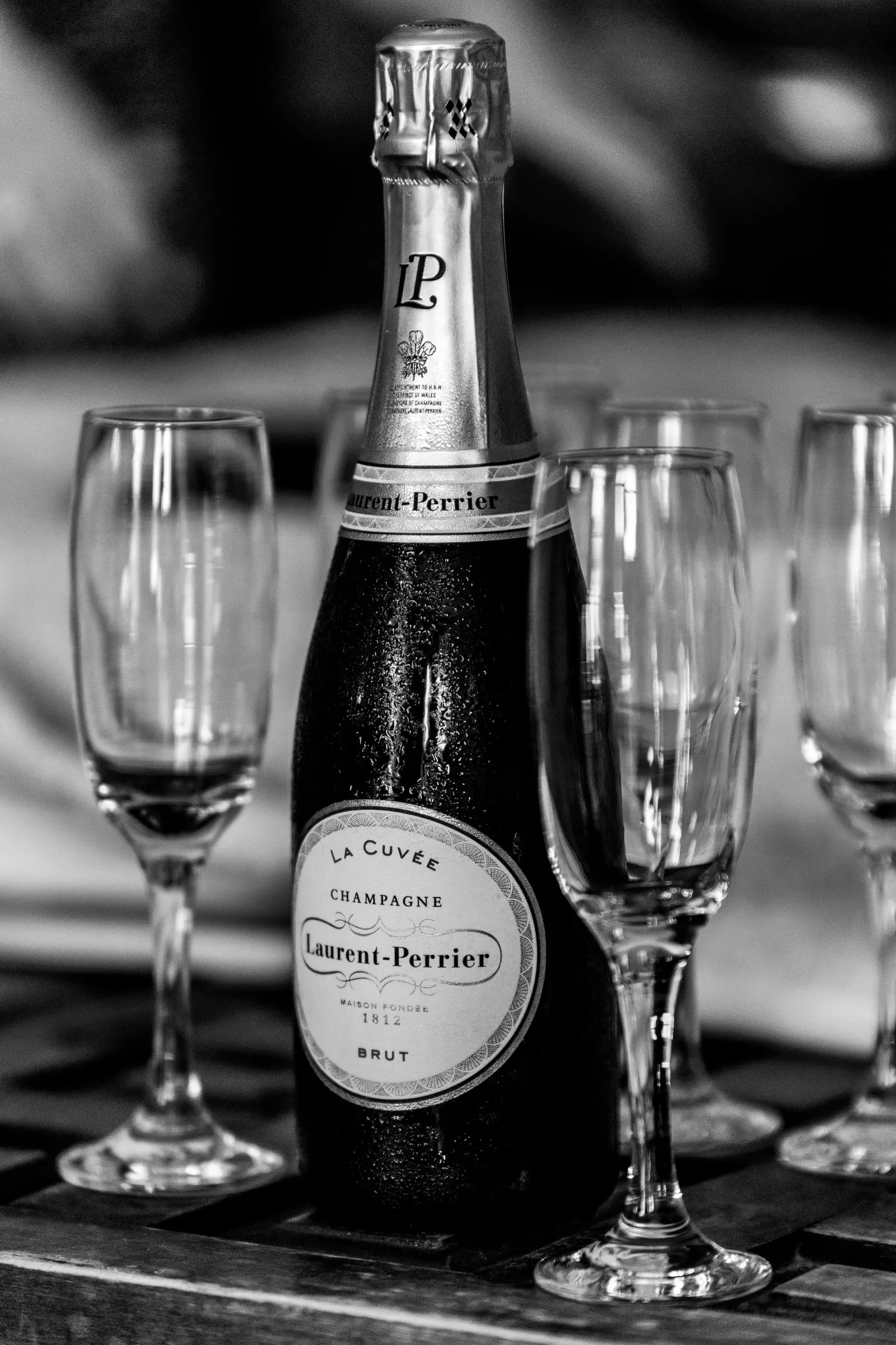 Una botella de champán rodeada de copas vacías listas para el brindis, en blanco y negro, Hacienda San José, Mijas