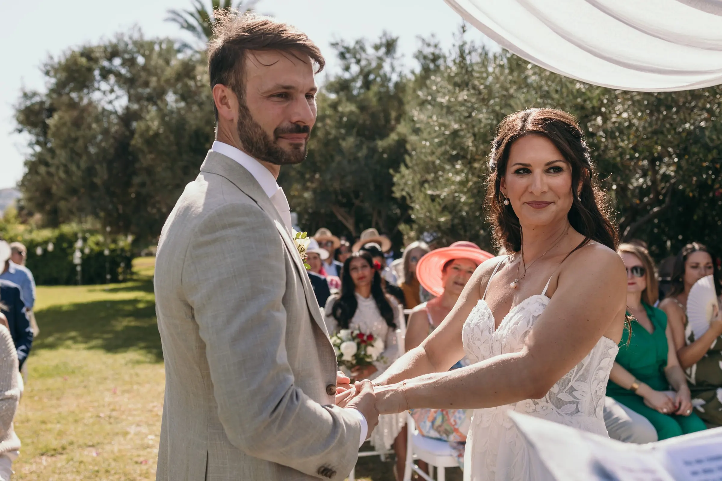 Los novios se cogen de las manos durante los votos ante los invitados sentados, Hacienda San José, Mijas