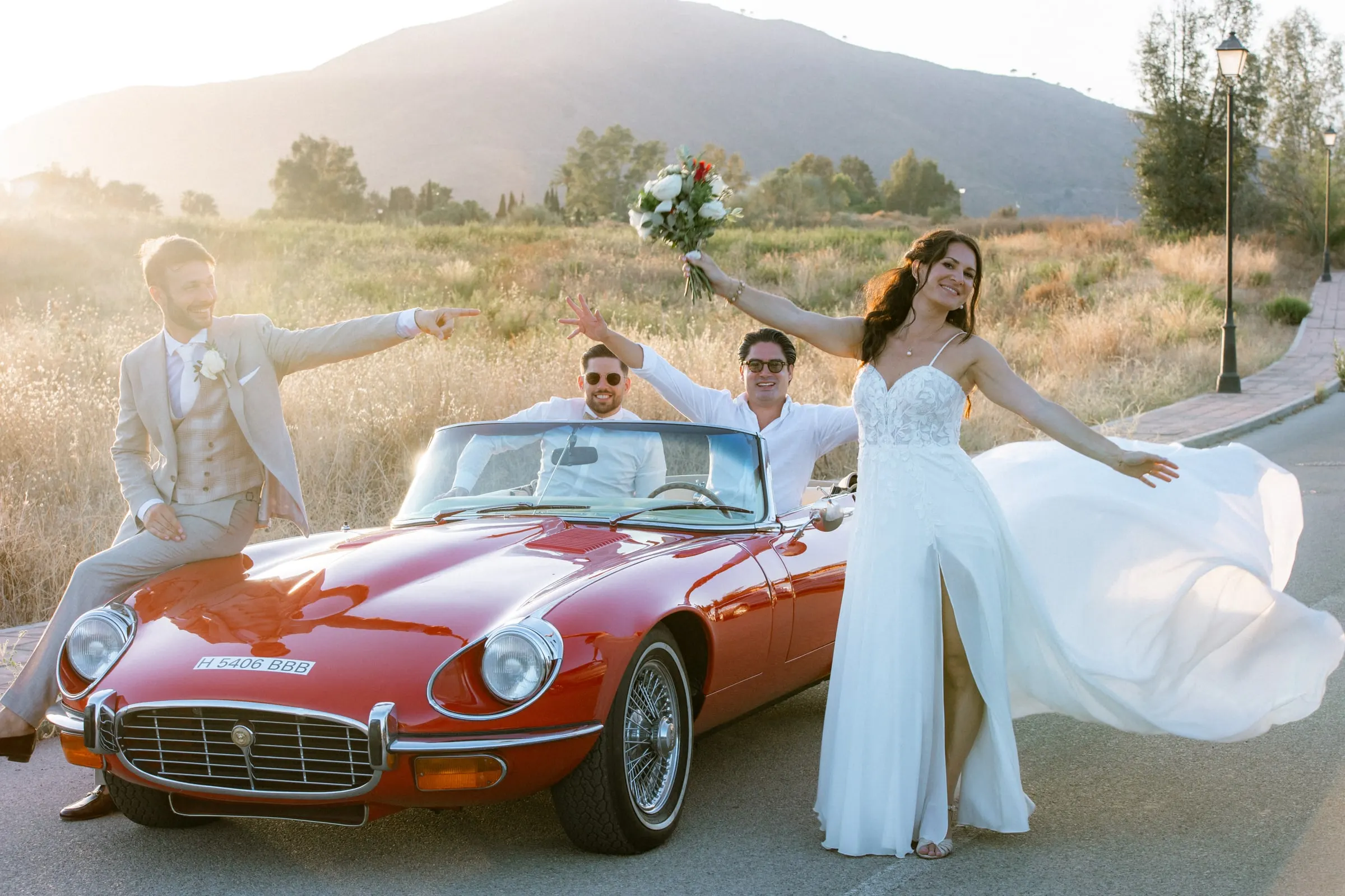 Los novios y sus amigos celebran alrededor de un descapotable rojo antiguo al sol de la tarde, Hacienda San José, Mijas