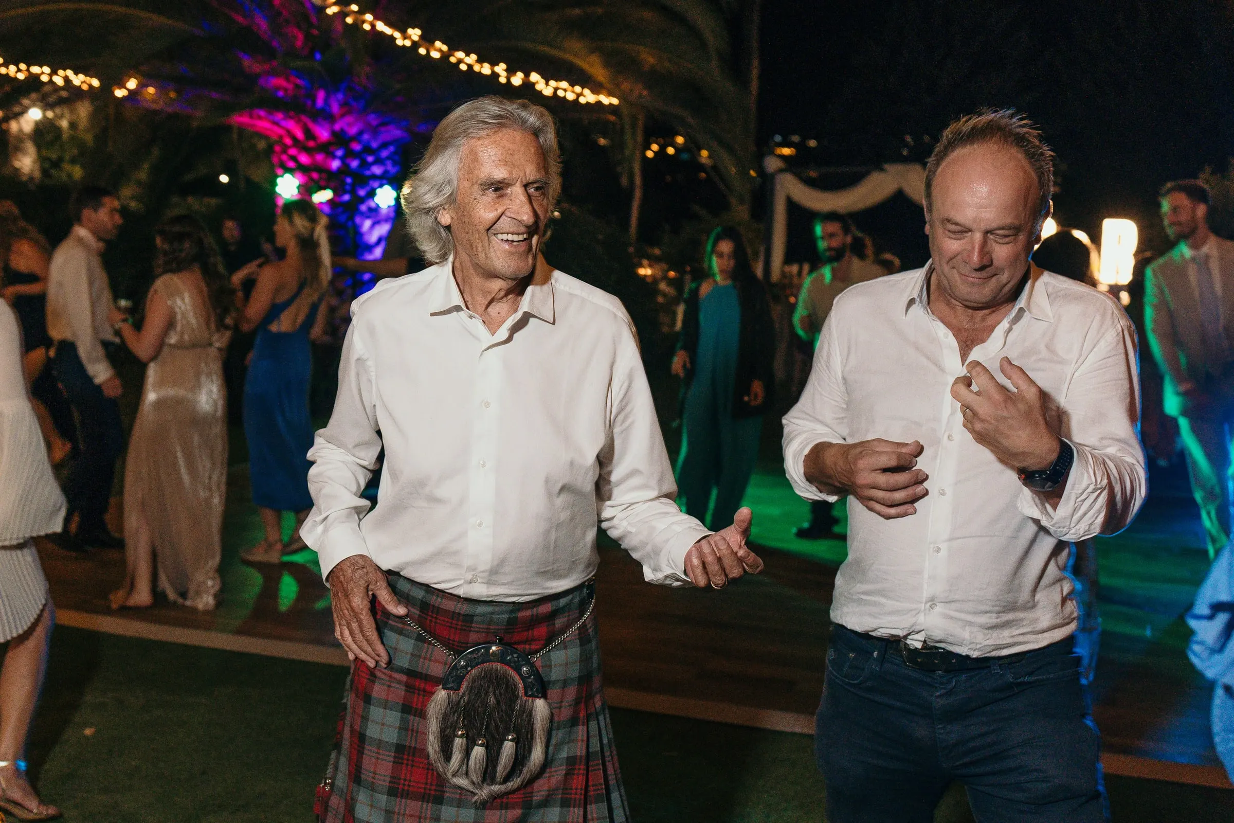 Two guests dancing, one in a kilt, under coloured party lights at Hacienda San José, Mijas