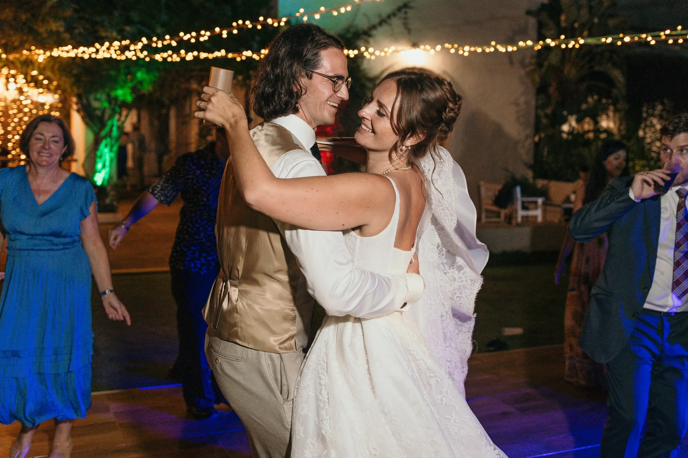 Bride and groom dancing close among guests under festoon lights at Hacienda San José, Mijas