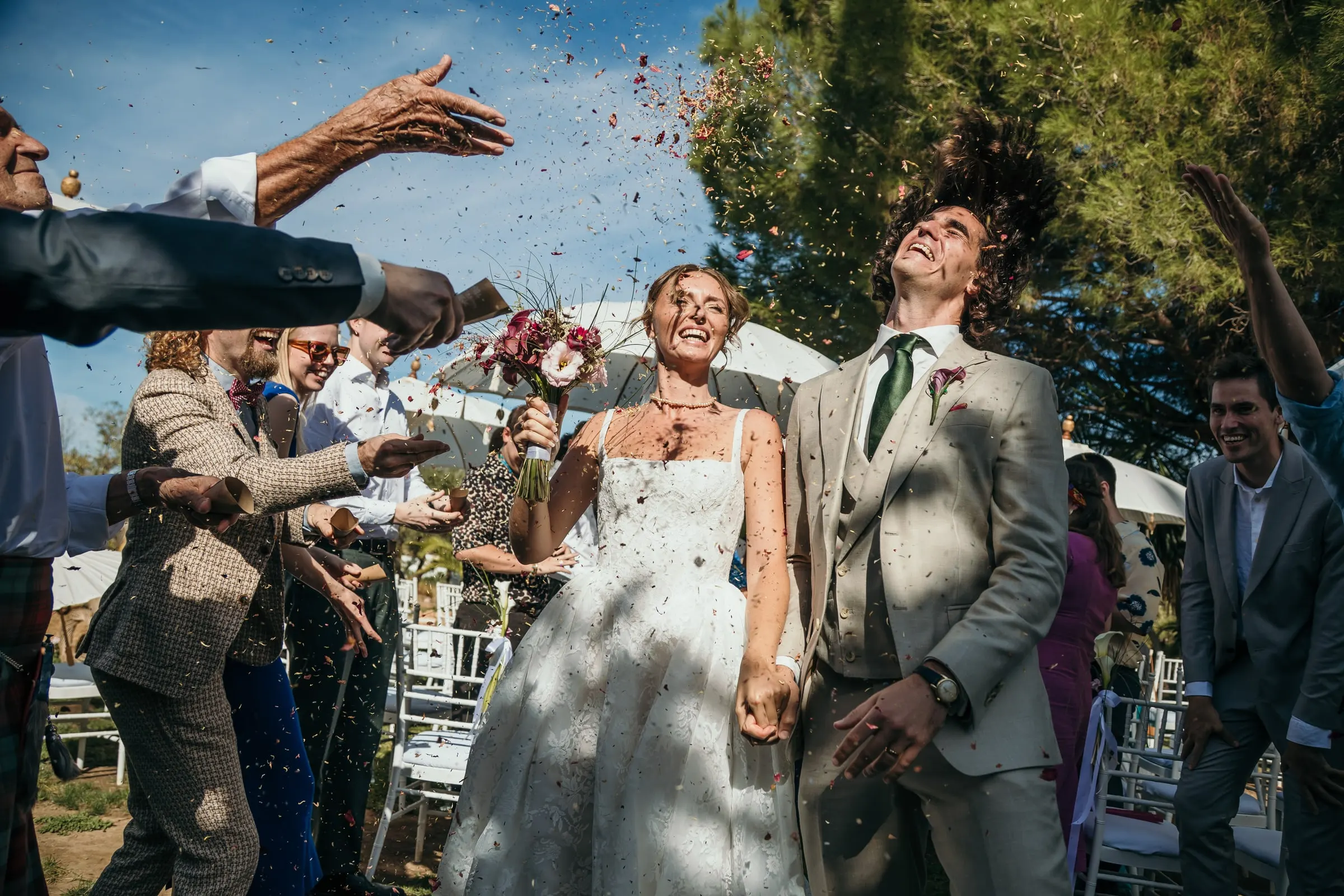 Bride and groom laughing under a burst of confetti as they leave the ceremony, Hacienda San José, Mijas