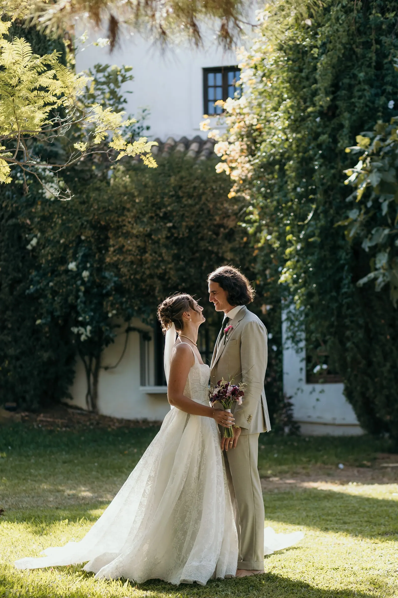 The couple face to face on the sunny lawn in front of the ivy-covered house, Hacienda San José, Mijas
