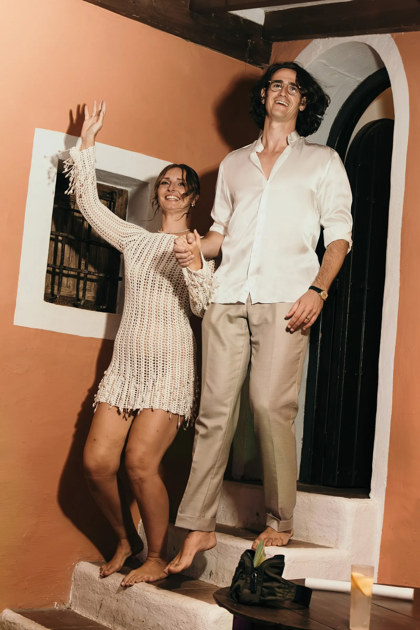 The bride in a crochet dress and the groom arriving barefoot at the evening party, Hacienda San José, Mijas