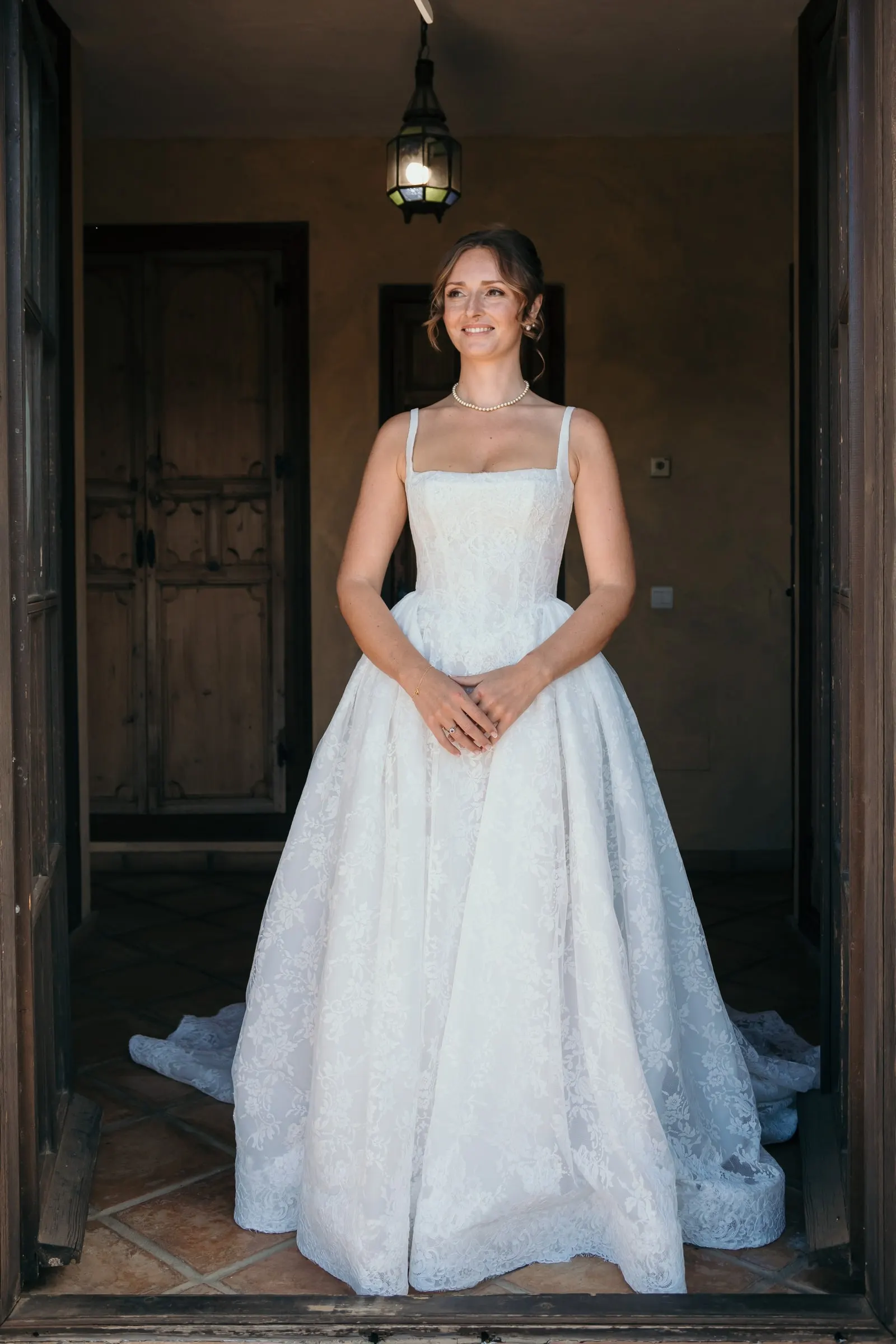 The bride standing in a dark wooden doorway in her full-skirted gown, Hacienda San José, Mijas