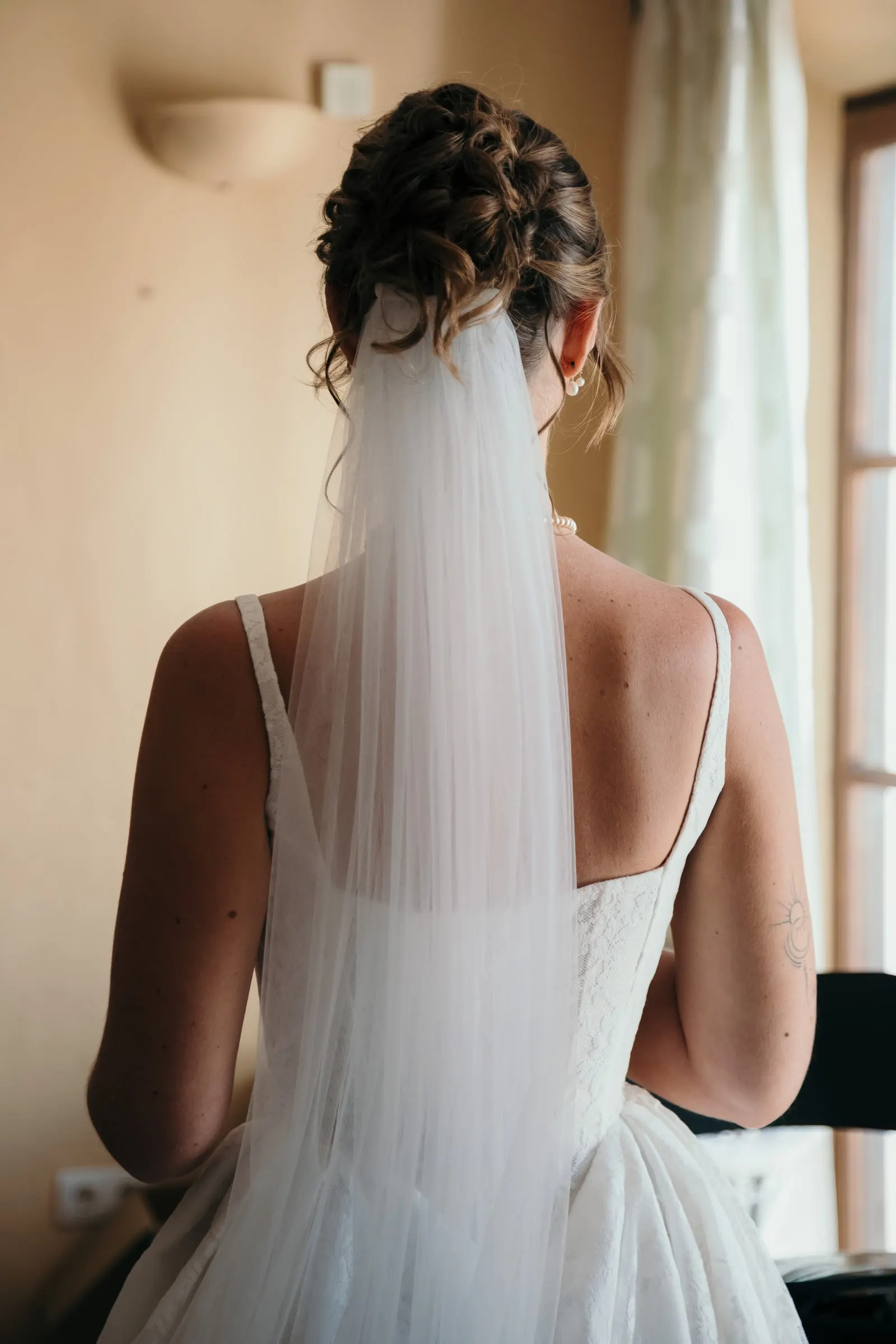 The bride seen from behind in her veil, looking towards the bright window, Hacienda San José, Mijas